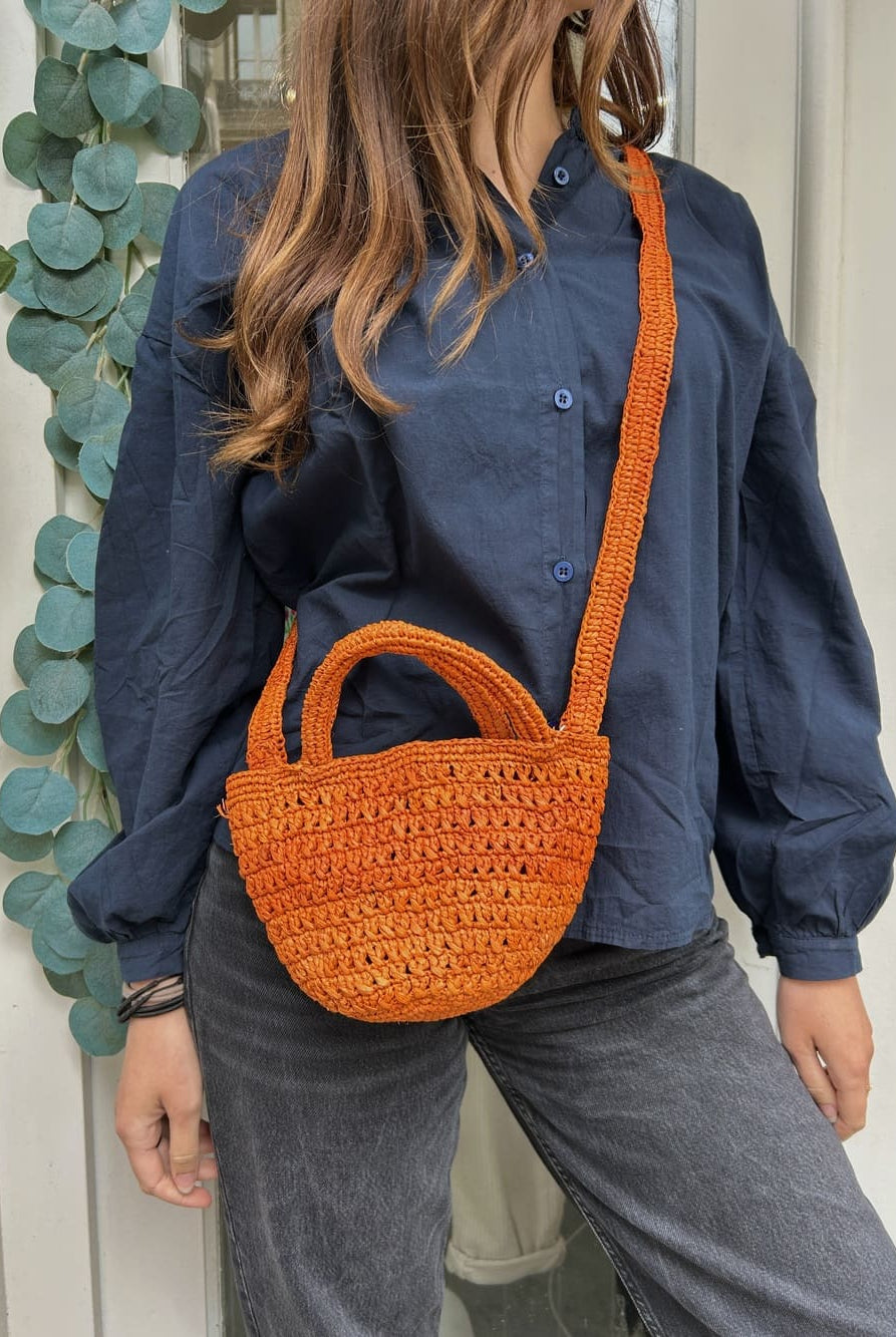 Femme portant le petit panier orange – Look estival et coloré