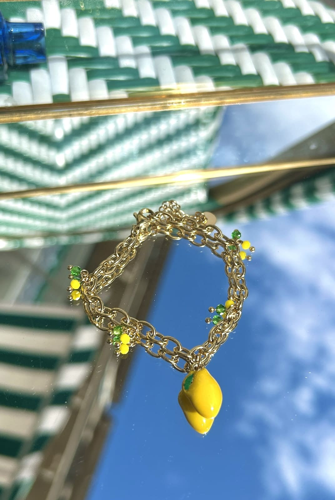 Bracelet breloque citron avec breloque fruitée colorée sur chaîne dorée, exposé sur fond clair