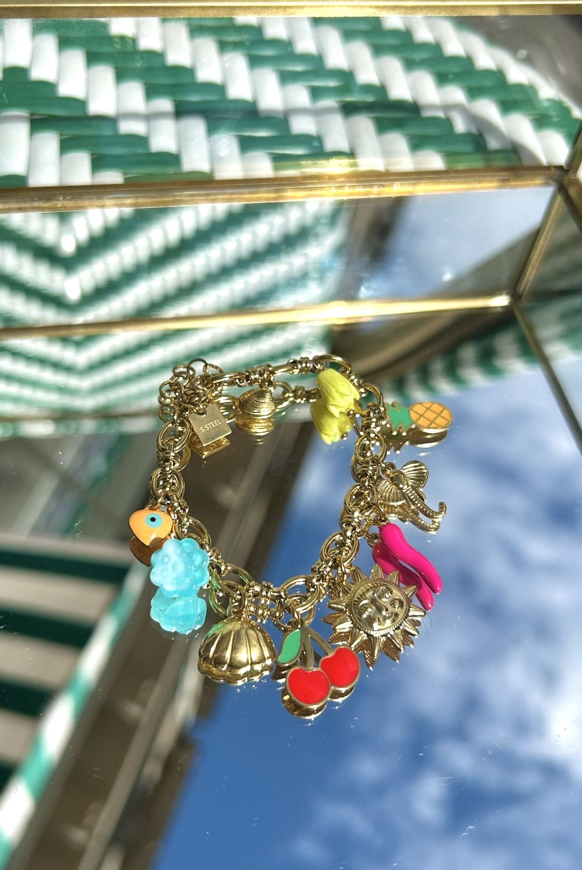 Bracelet breloque avec charms soleil et ananas, exposé sur fond clair