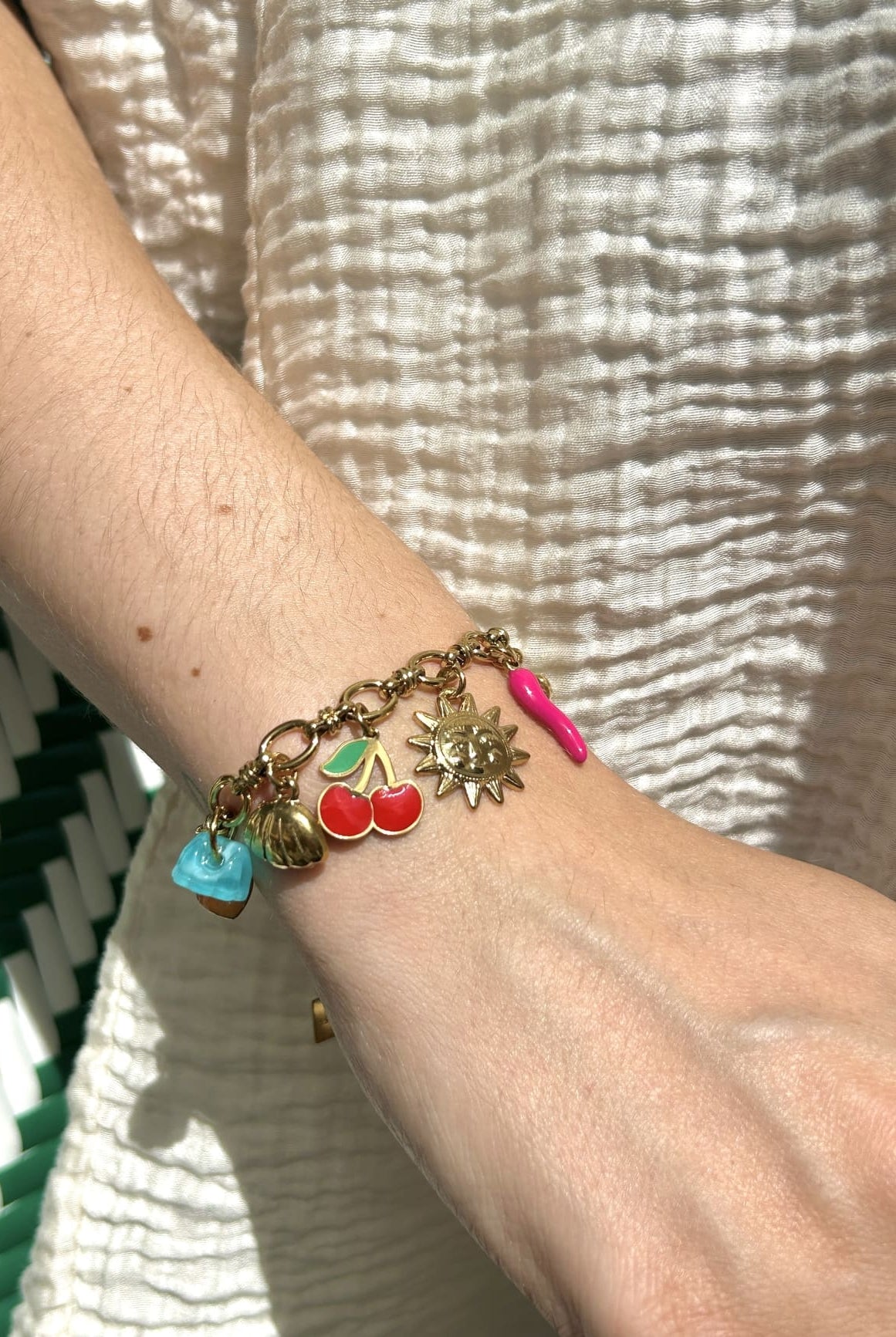 Bracelet breloque soleil et ananas porté au poignet d’une femme