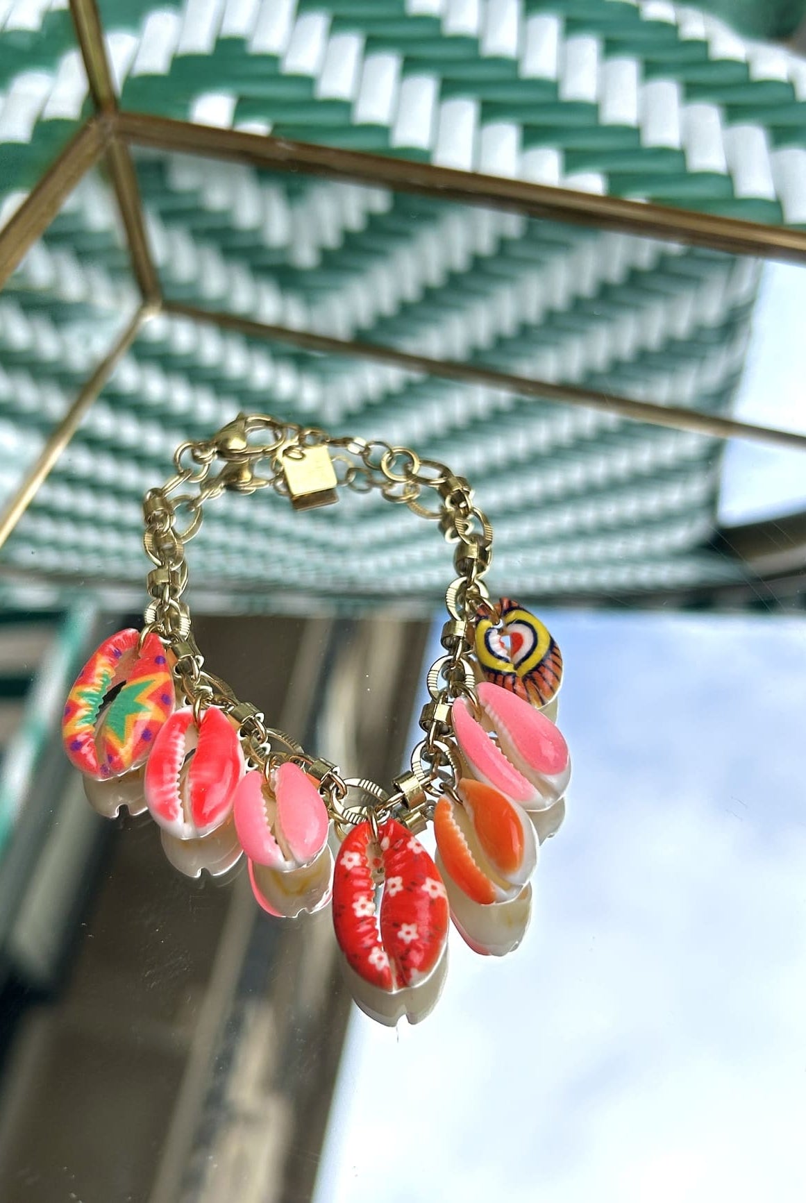 Bracelet à chaîne dorée fine avec breloque coquillage, exposé sur fond clair