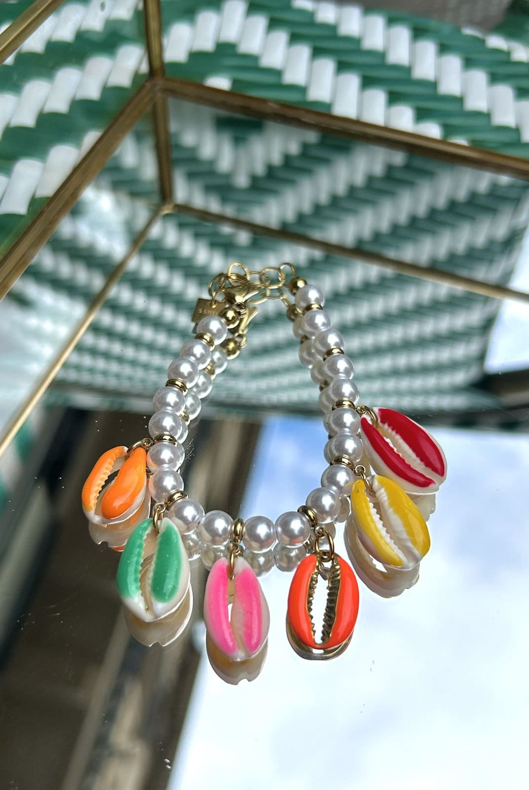 Bracelet coquillage avec perles blanches, posé sur fond clair