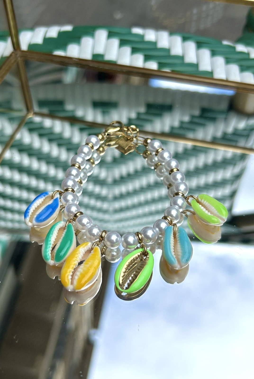 Bracelet avec coquillage oversize, perles vertes et blanches, exposé sur fond clair