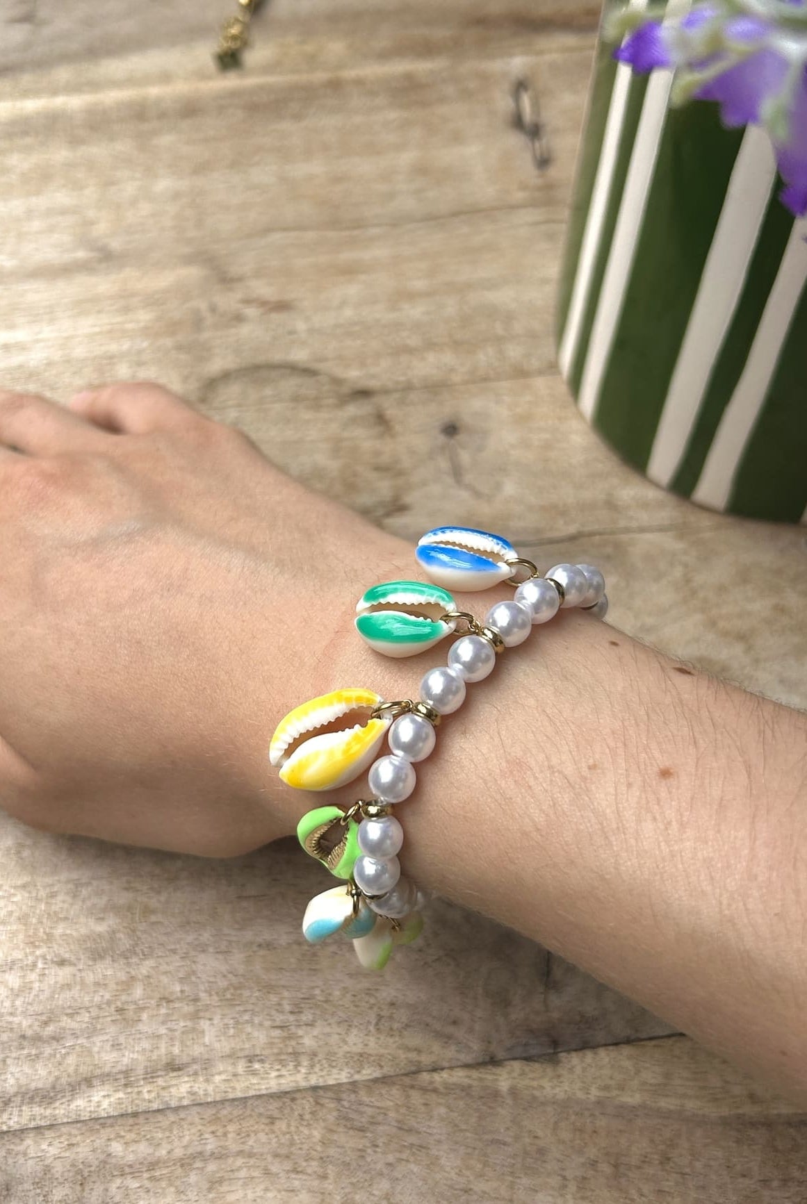 Bracelet coquillage aux perles vertes porté au poignet d’une femme