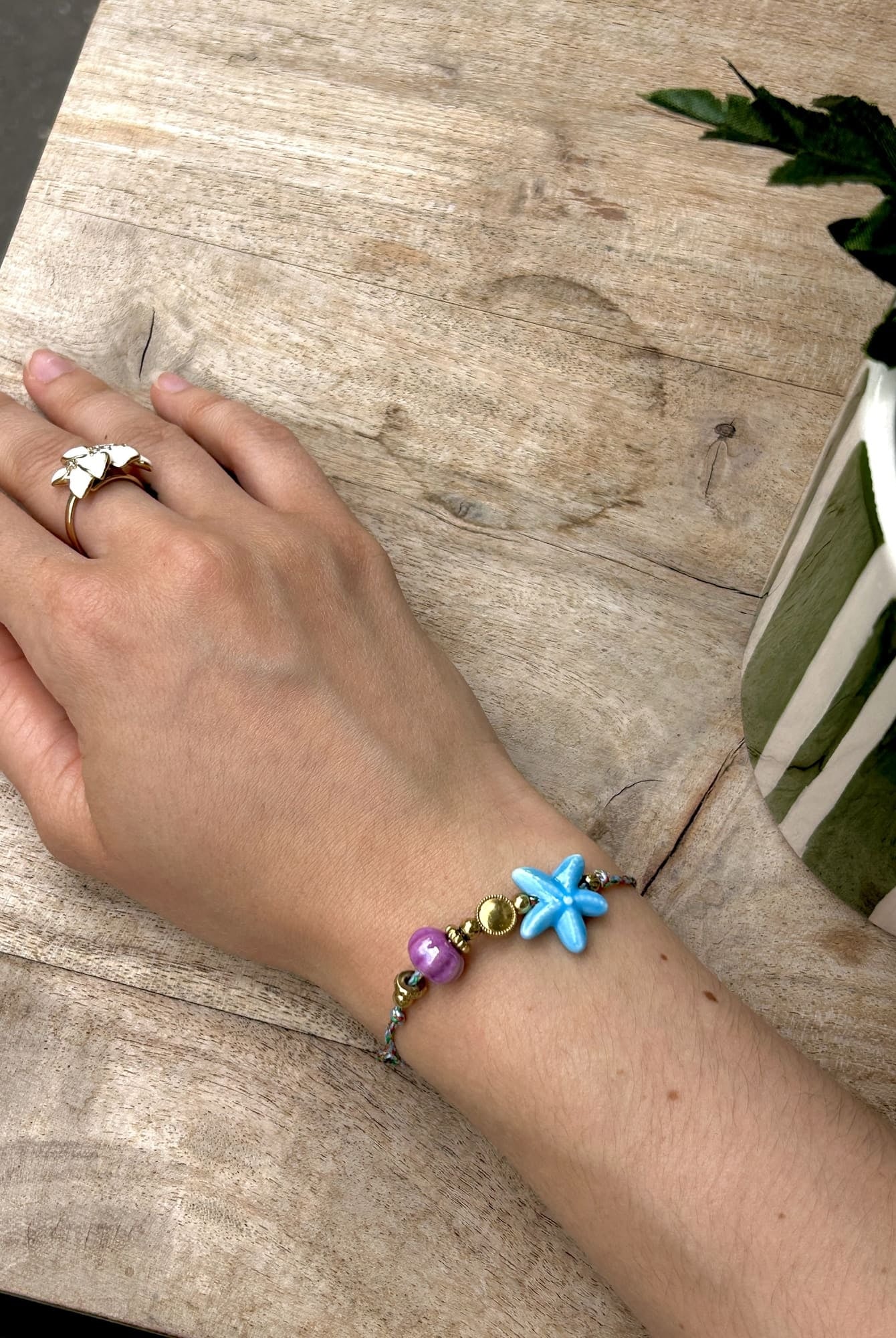 Bracelet perle étoile de mer sur cordon porté au poignet