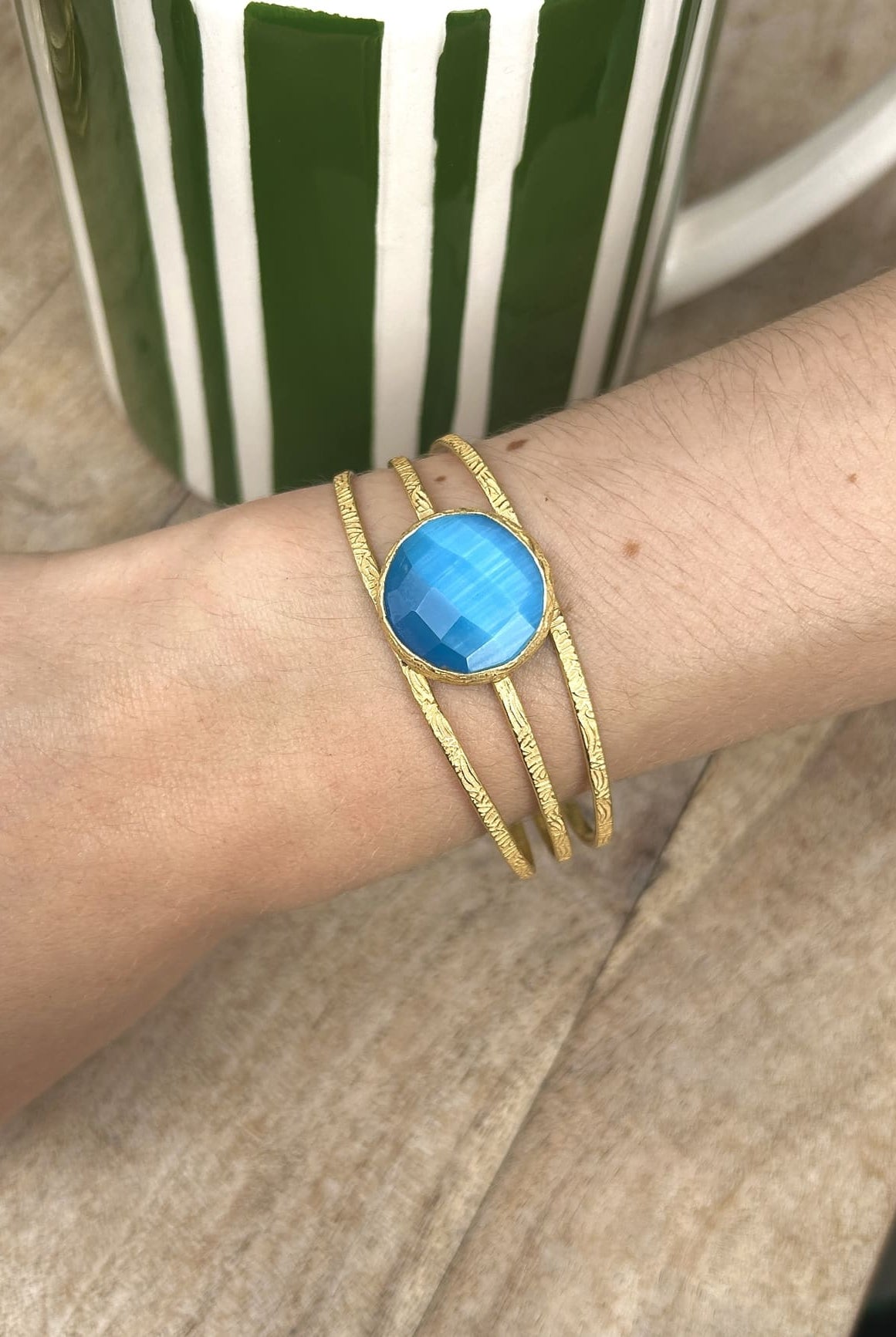 Bracelet en laiton avec pierre semi-précieuse bleue porté au poignet
