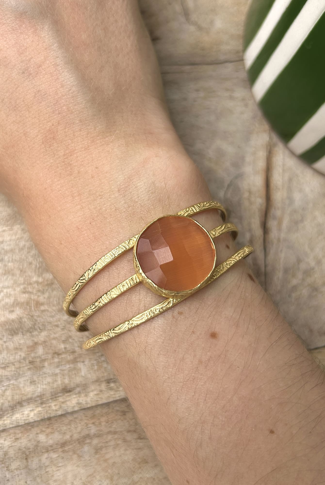 Bracelet manchette en laiton doré et pierre orange au poignet