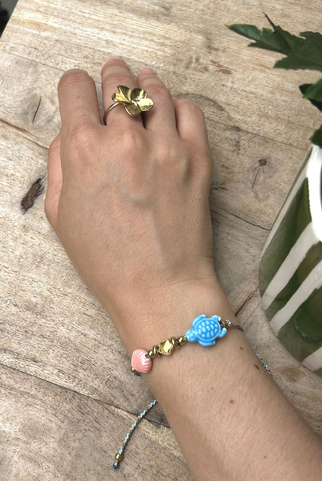 Bracelet cordon tortue bleu porté au poignet d’une femme