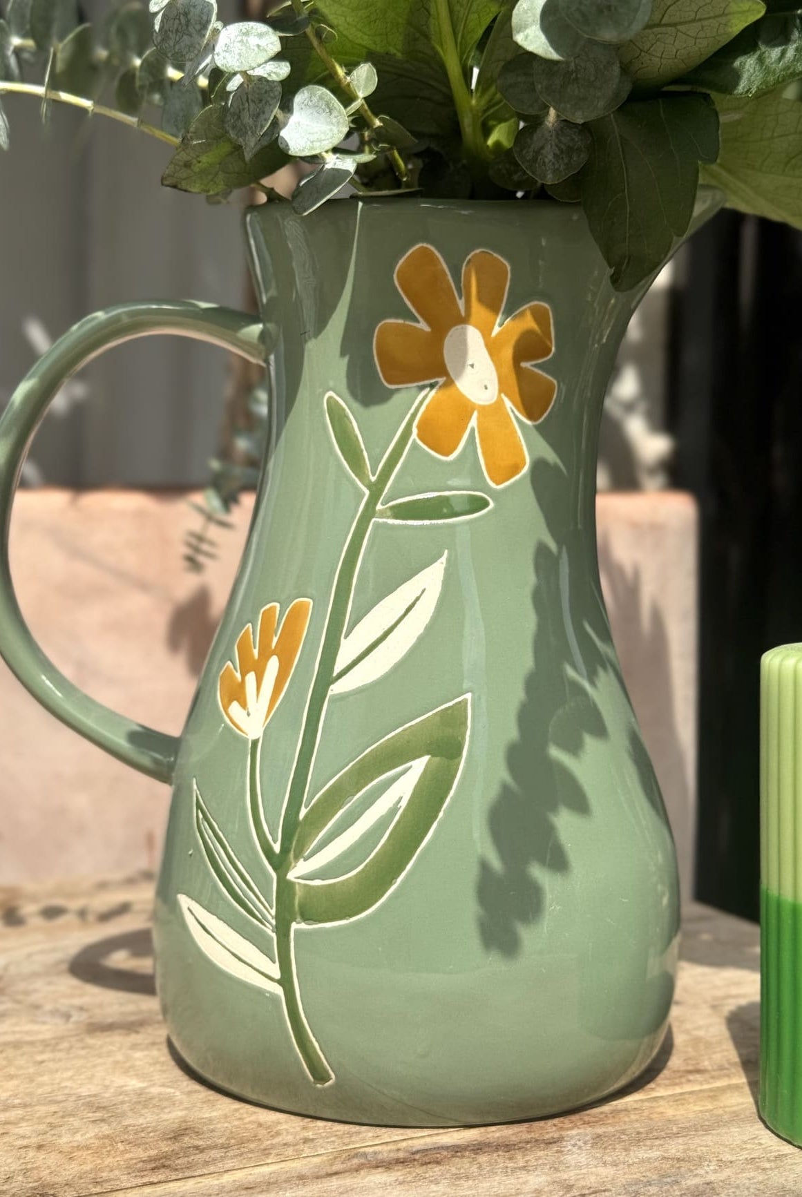 Carafe en céramique verte avec motifs floraux colorés – vue de face