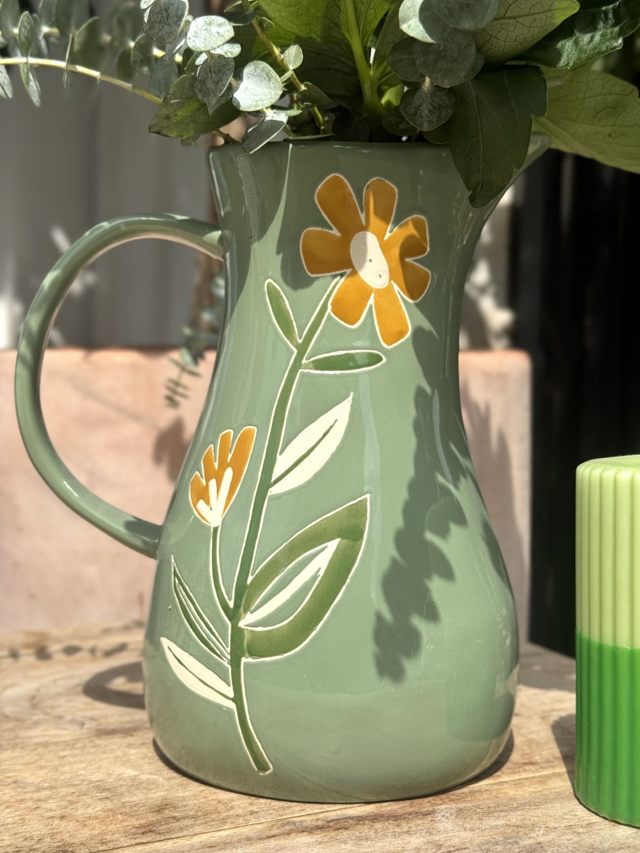 Carafe en céramique verte avec motifs floraux colorés – vue de face