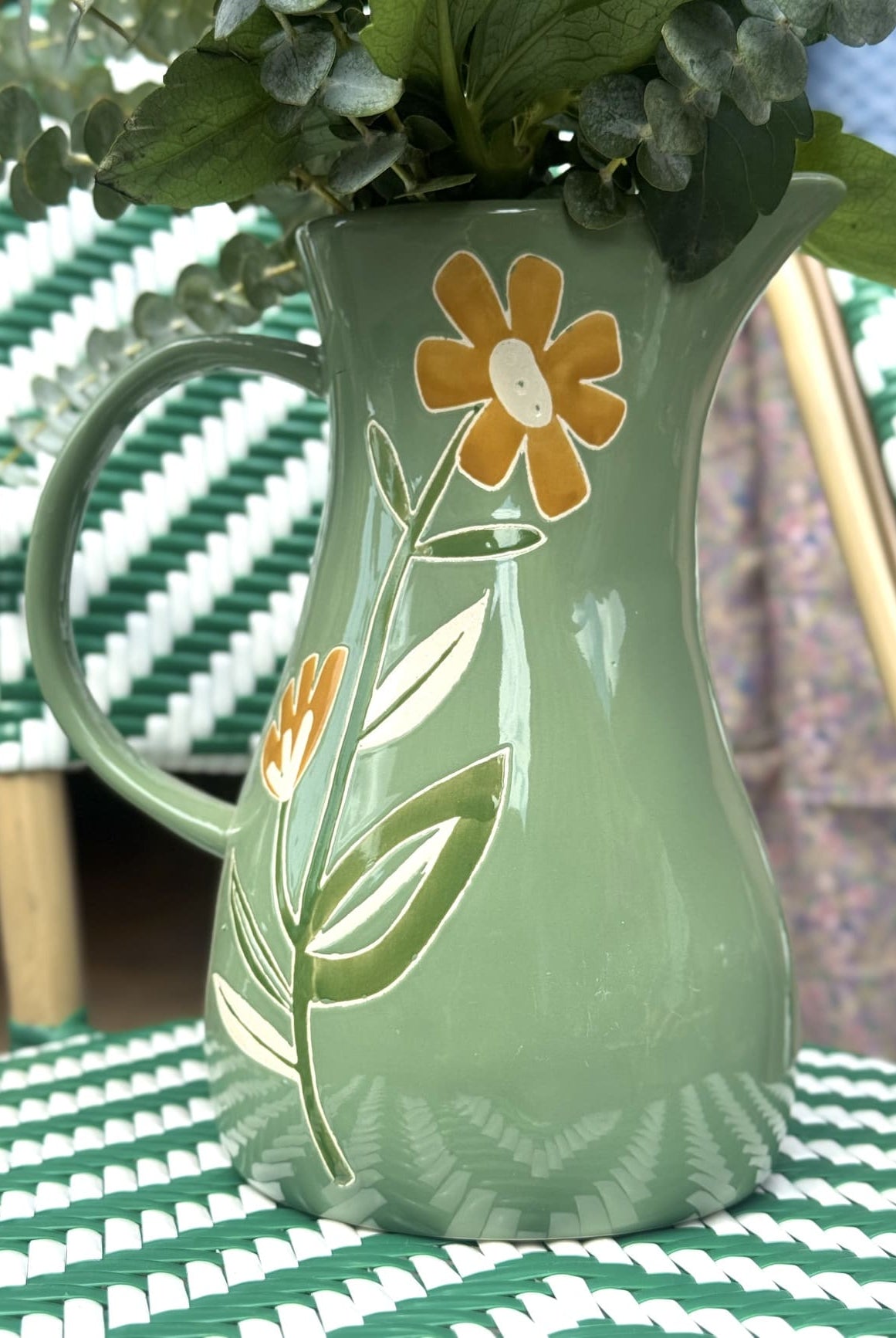 Détail des fleurs peintes à la main sur carafe en céramique verte