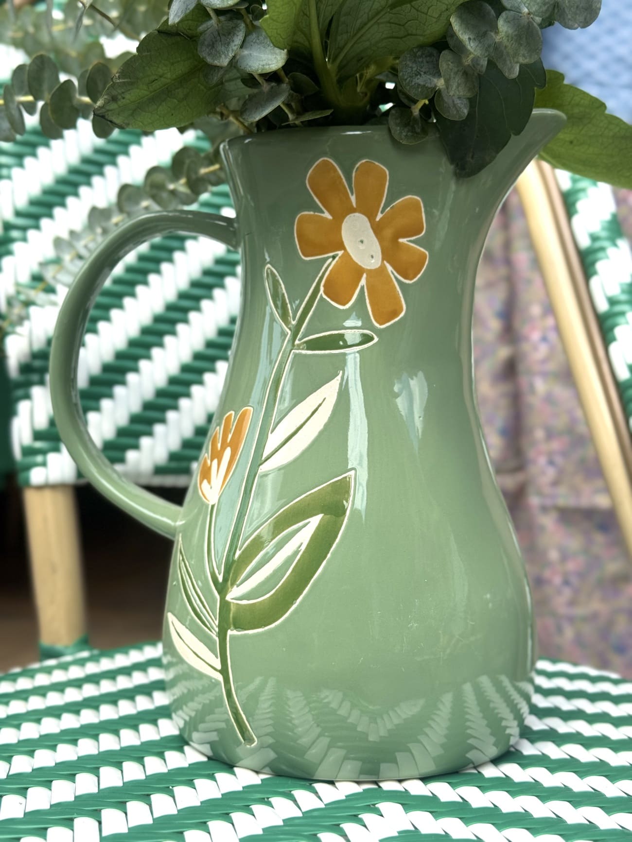 Détail des fleurs peintes à la main sur carafe en céramique verte