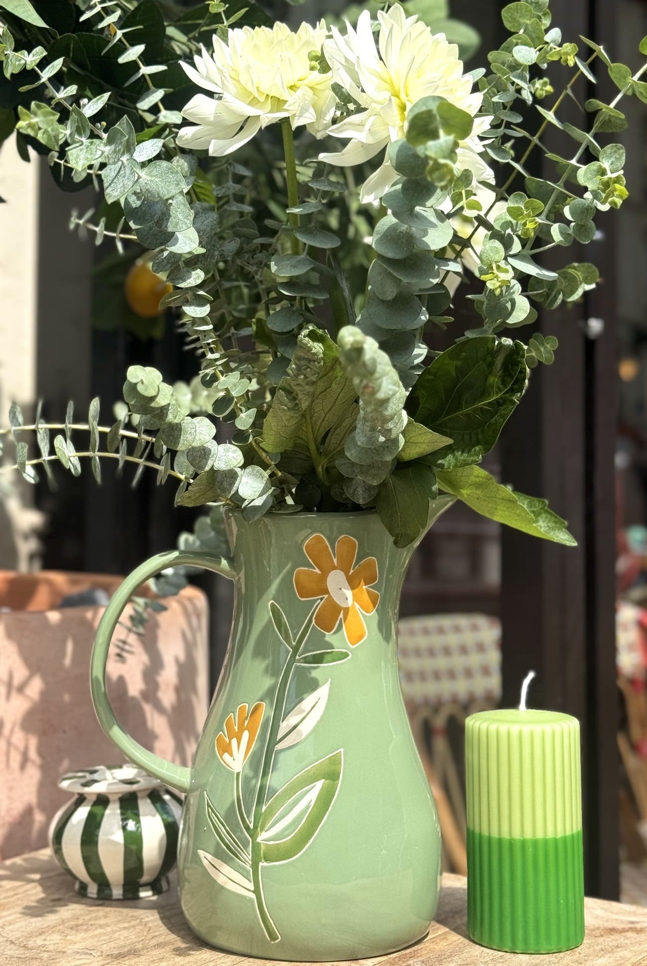 Carafe verte fleurie utilisée comme vase avec un bouquet de fleurs