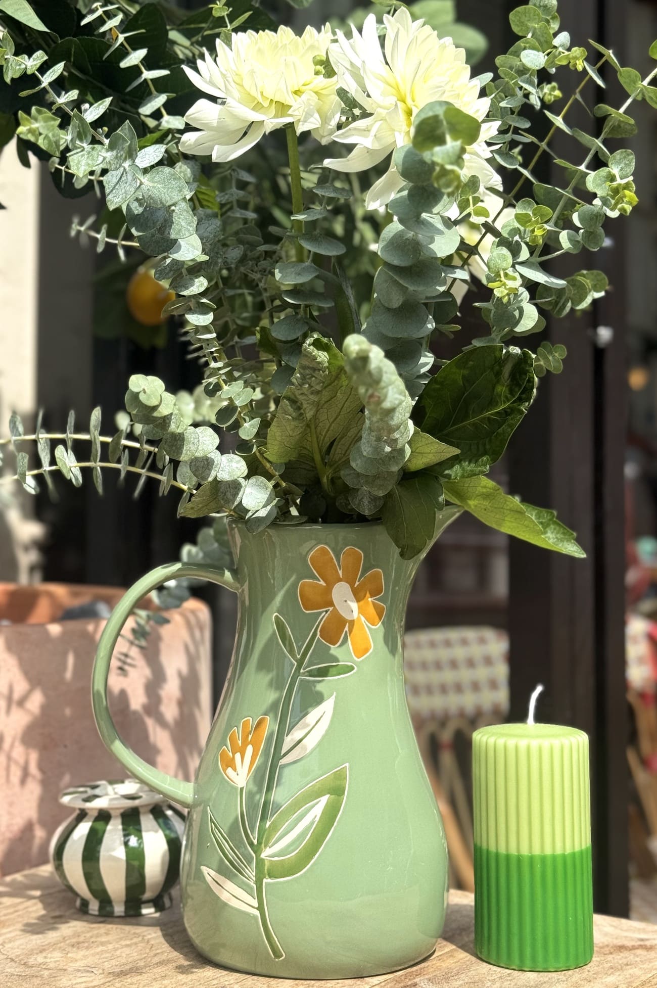 Carafe verte fleurie utilisée comme vase avec un bouquet de fleurs