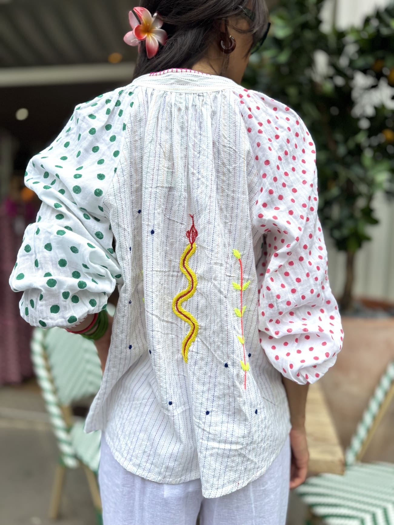Détail des broderies serpent, fleur et étoiles sur le dos de la chemise blanche à pois.