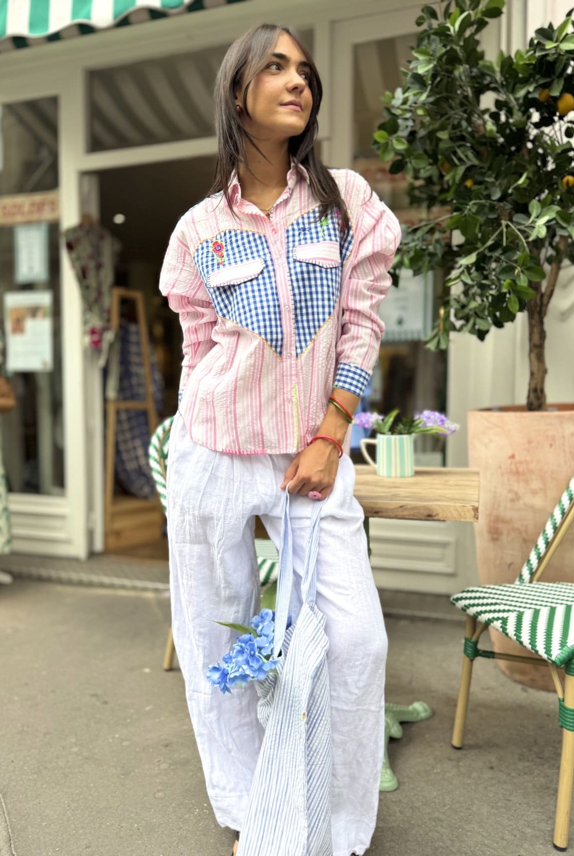 Chemise à rayures roses et incrustée de vichy bleu portée avec un pantalon blanc.