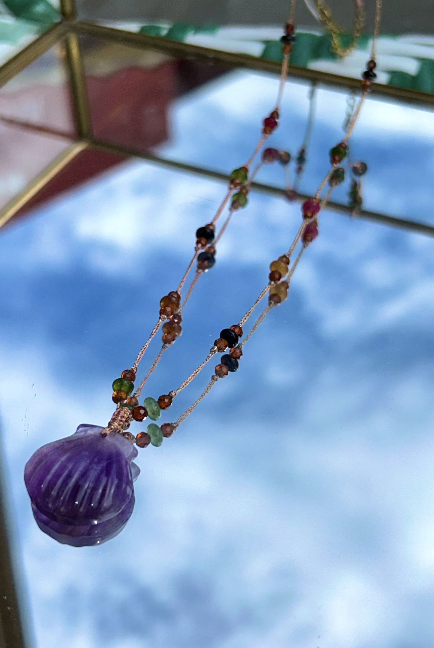 Gros plan du collier mettant en valeur les perles d'agate et le coquillage