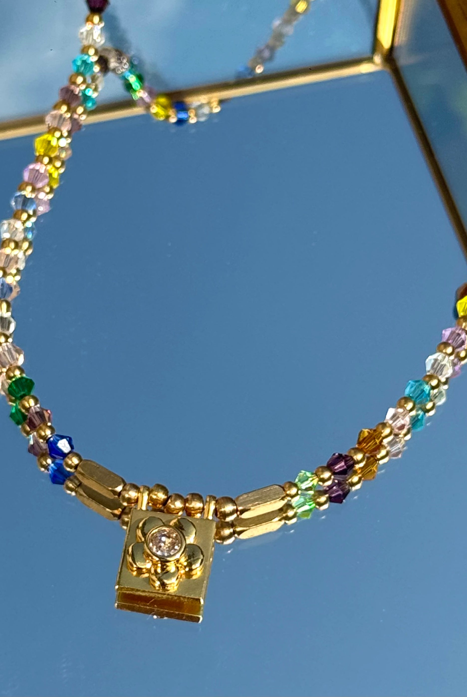 Gros plan sur le collier Daisy Square – détail du pendentif carré doré