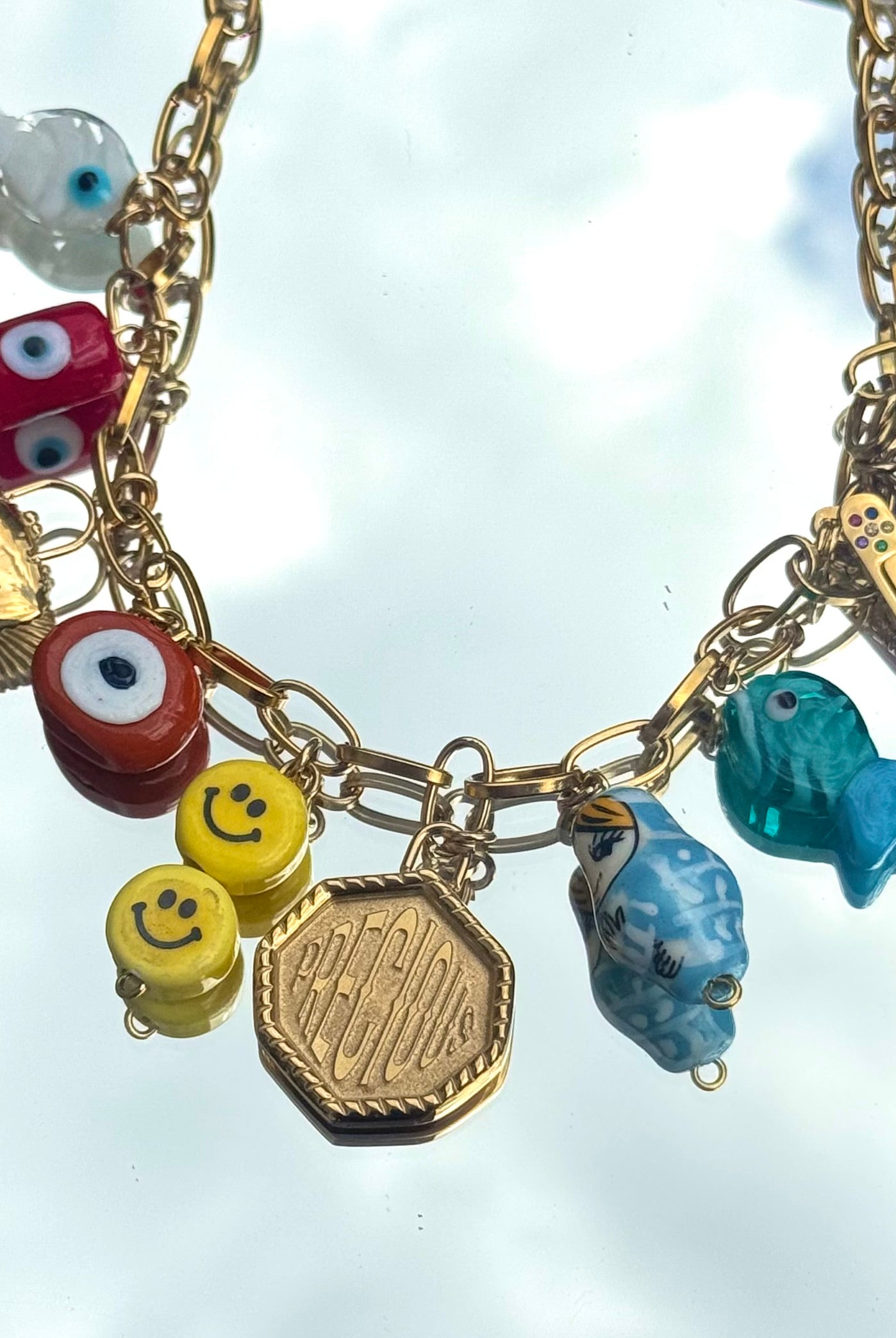 Gros plan du collier Kchoush avec 11 charms dorés symbolisant chance, guérison et prospérité