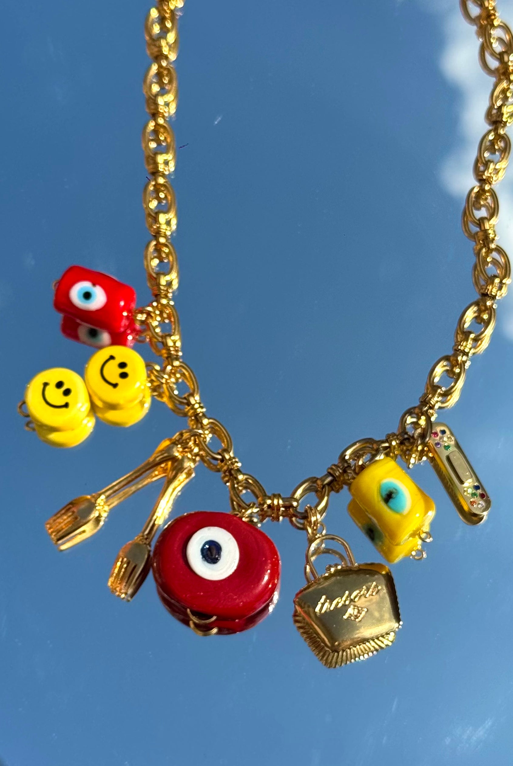 Gros plan du collier Kchoush avec 7 charms dorés symbolisant chance, guérison et prospérité