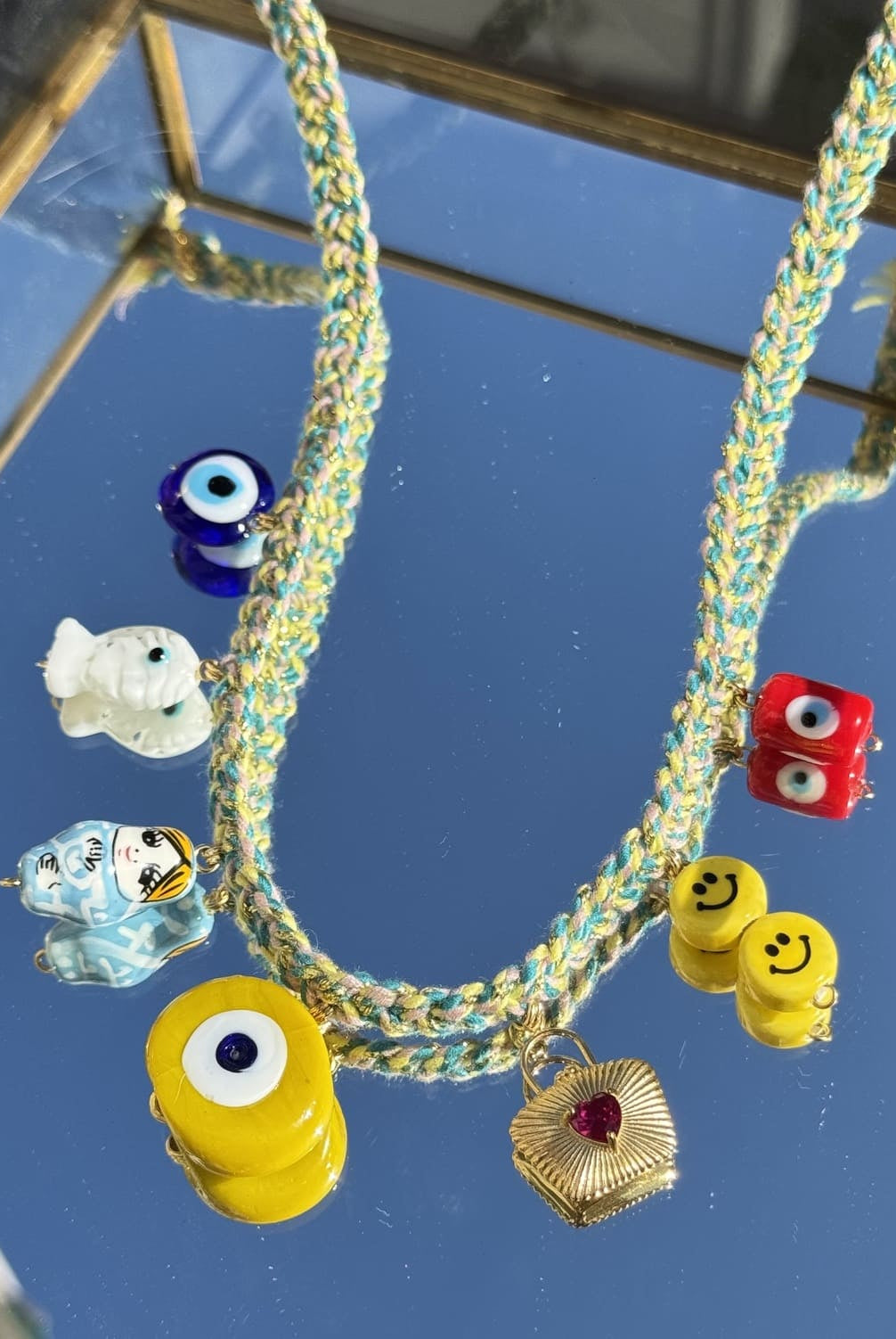 Gros plan sur le collier Kchoush jaune tressé et ses 7 charms