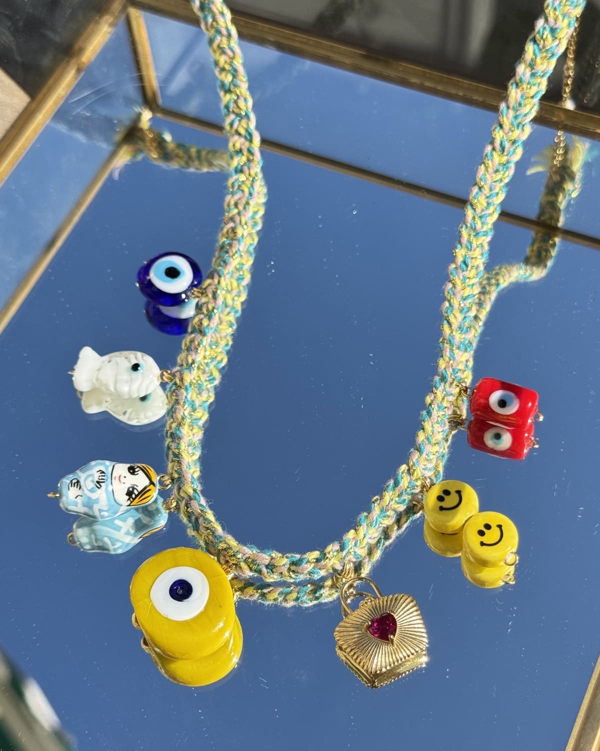 Gros plan sur le collier Kchoush jaune tressé et ses 7 charms