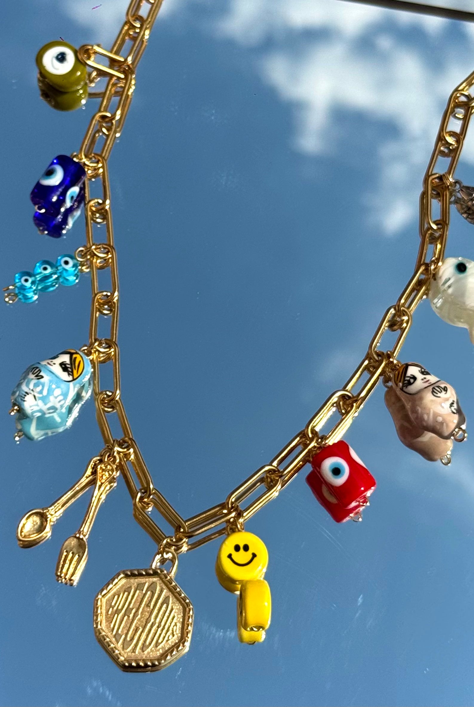 Gros plan sur les 11 charms du collier Mamie Esther – symboles de prospérité et poisson précieux