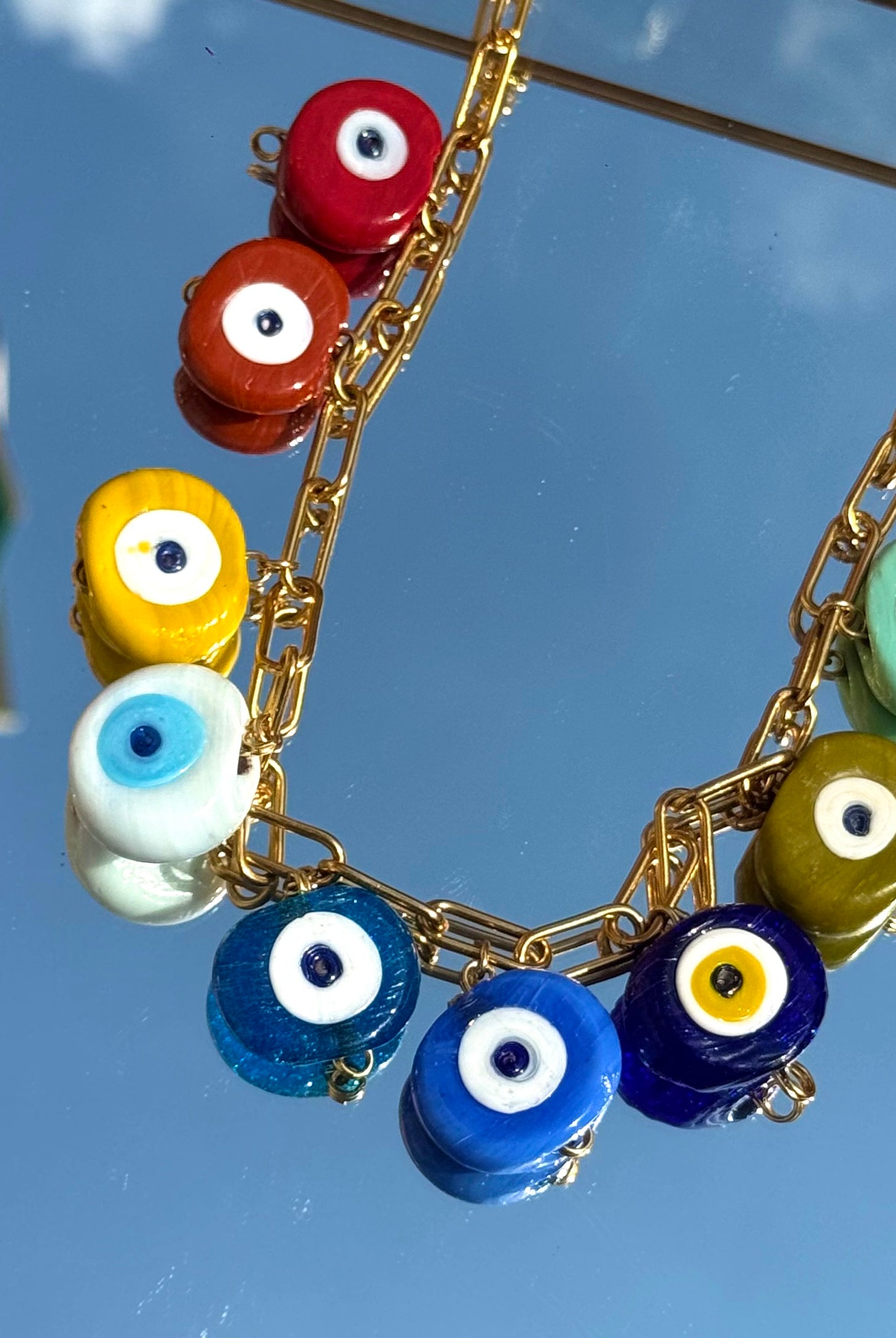 Gros plan sur les charms œil grec du collier Mamie Esther – symbole de protection