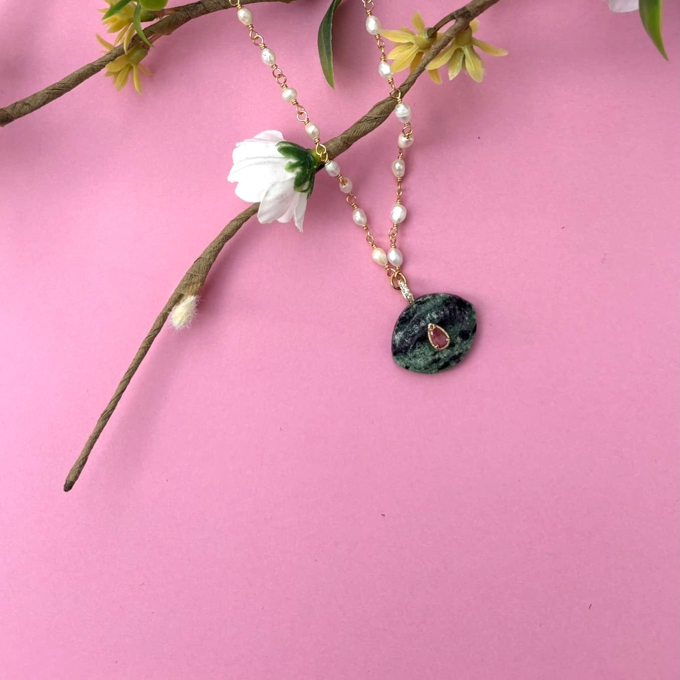 Collier en nacre et pierre d'agate sur une branche vue de face