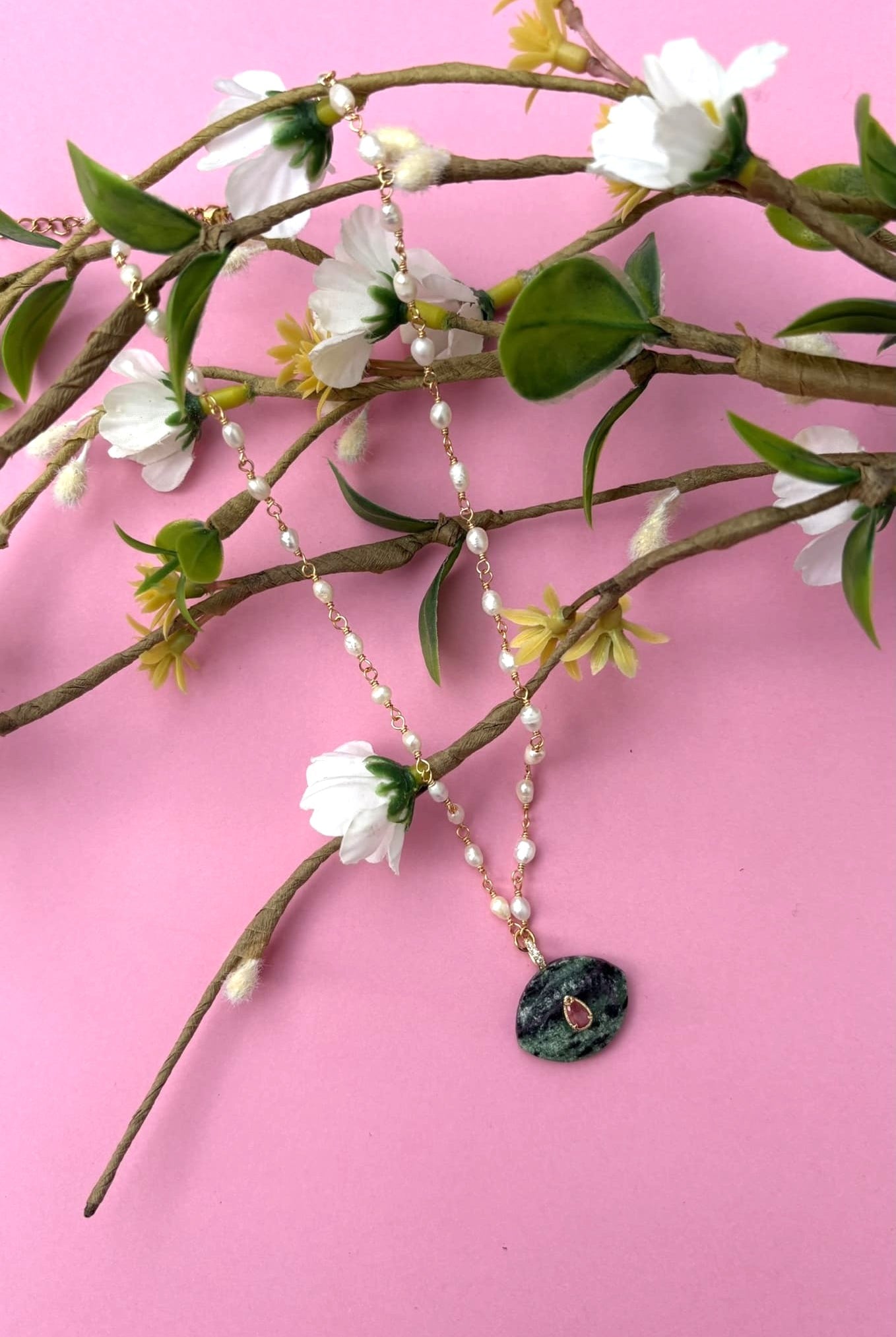 Collier en nacre et pierre d'agate sur une branche vue de face