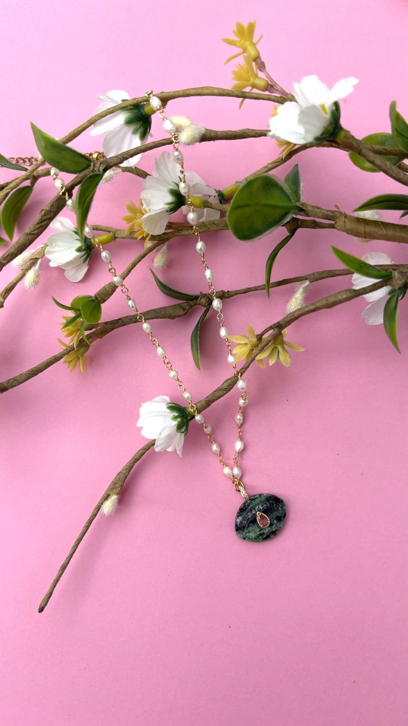 Collier en nacre et pierre d'agate sur une branche vue de face