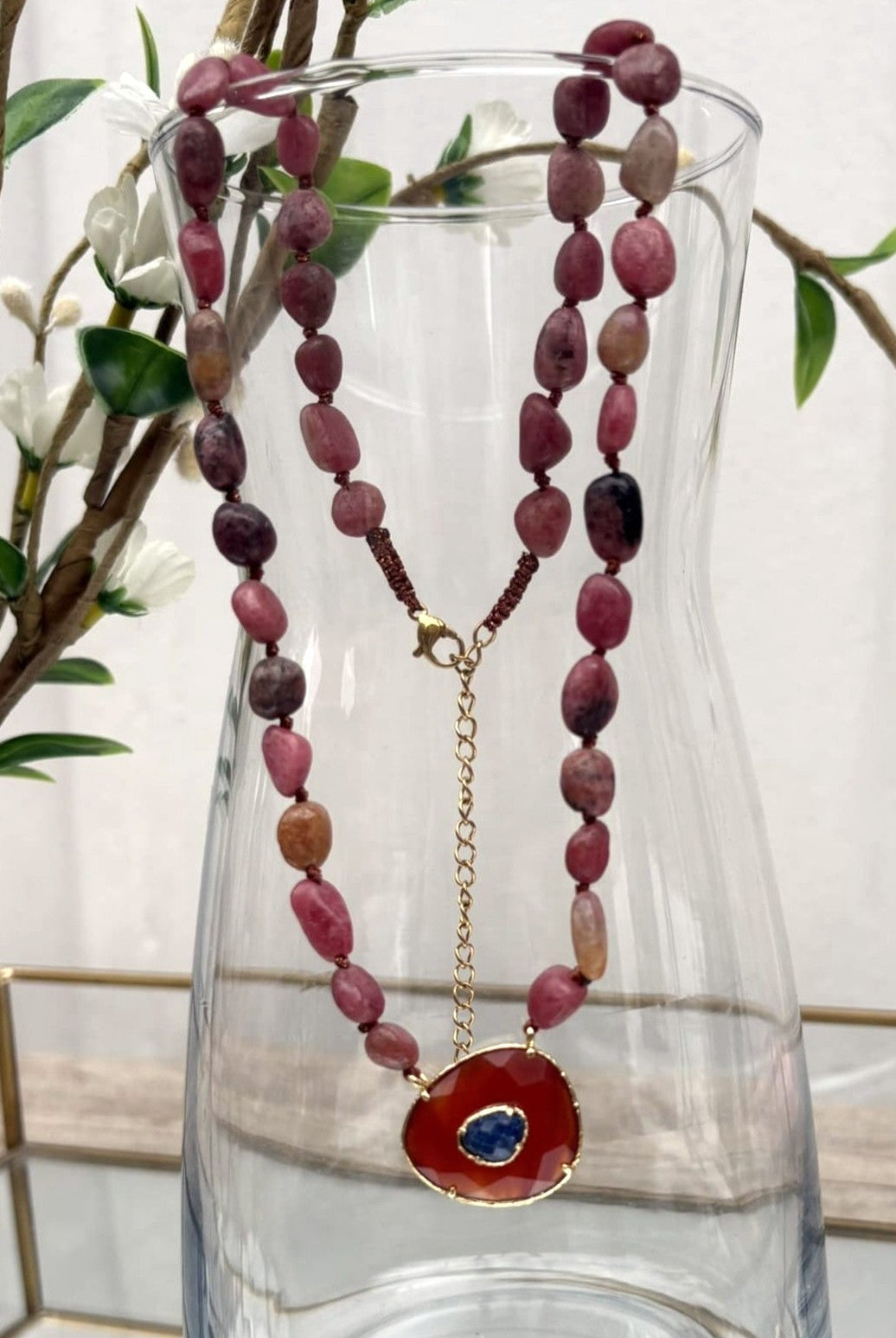 Collier perle naturelle rose suspendu à un vase vue de face