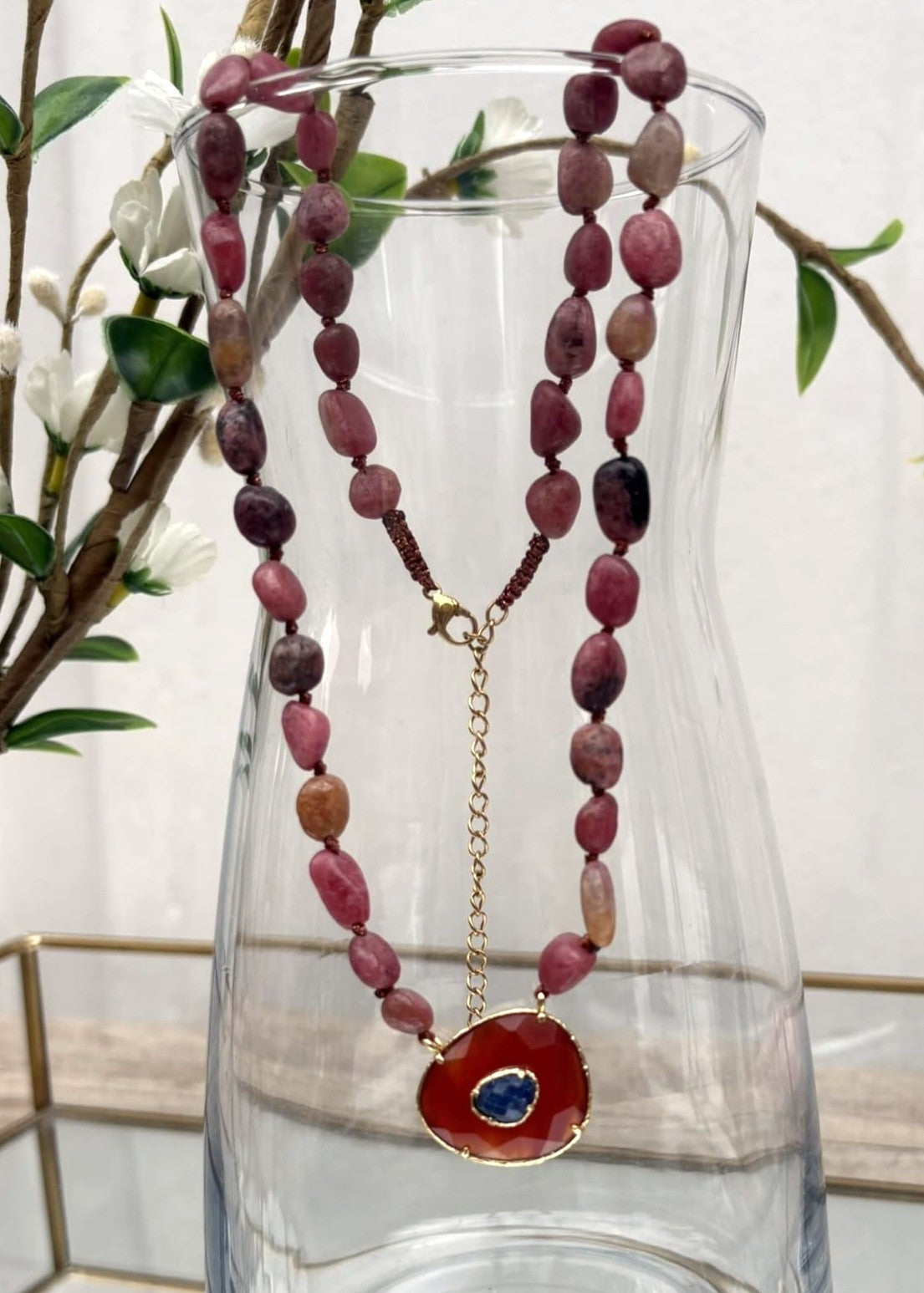 Collier perle naturelle rose suspendu à un vase vue de face