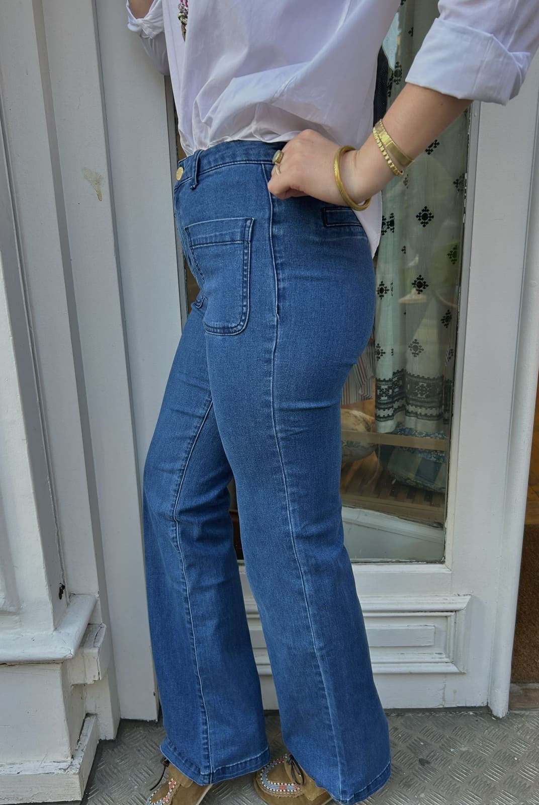 Détail du jean flare bleu foncé, silhouette allongée et taille haute