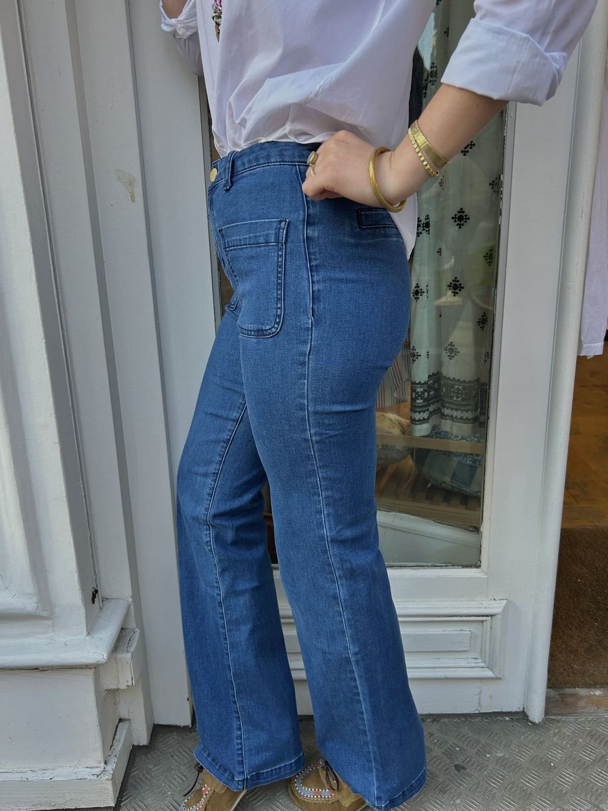 Détail du jean flare bleu foncé, silhouette allongée et taille haute