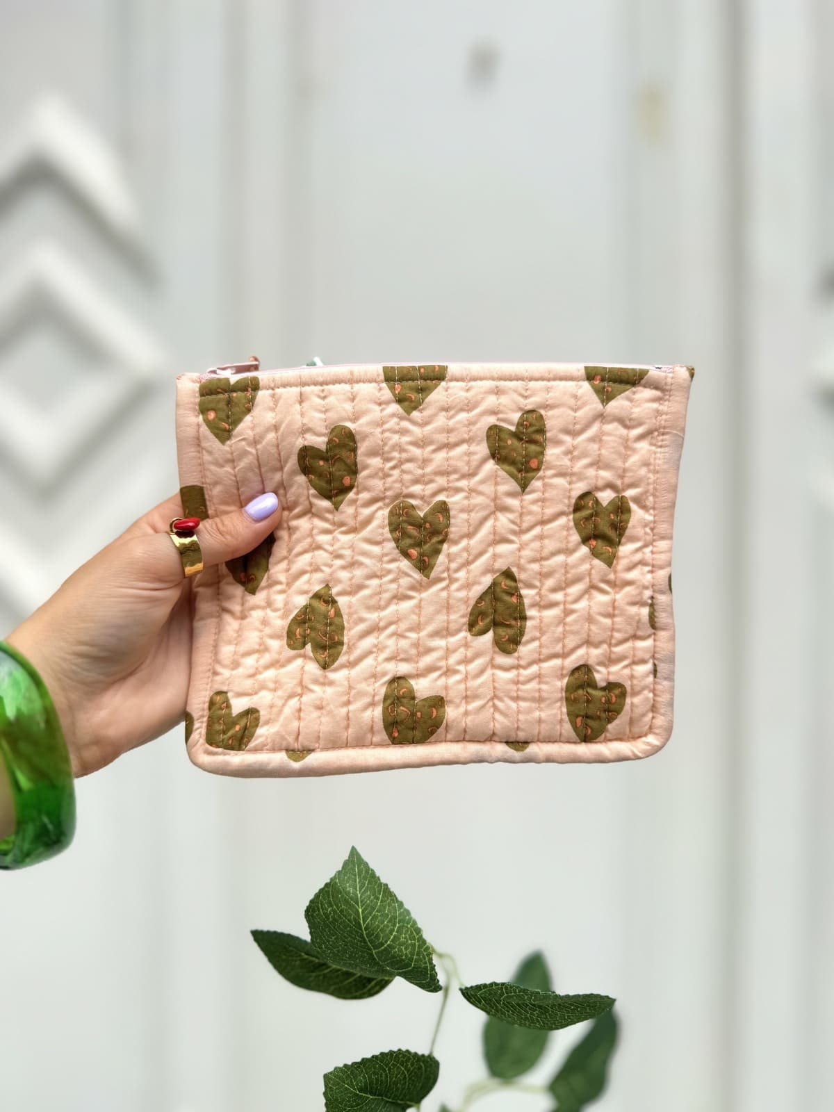Femme présentant une pochette rose matelassée avec imprimé cœurs camel