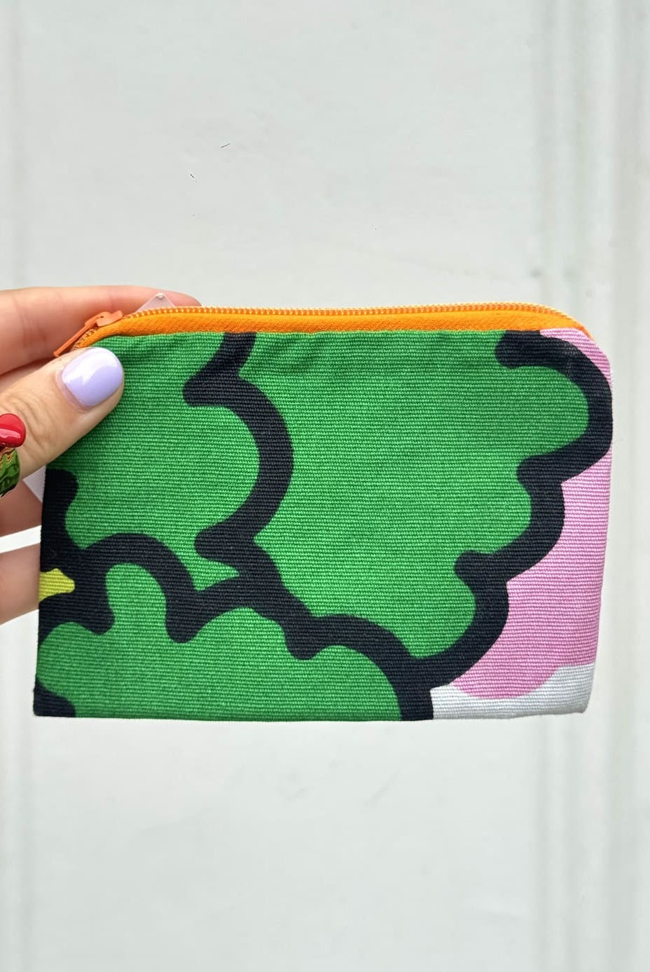 Main présentant une mini pochette verte upcyclée à la main