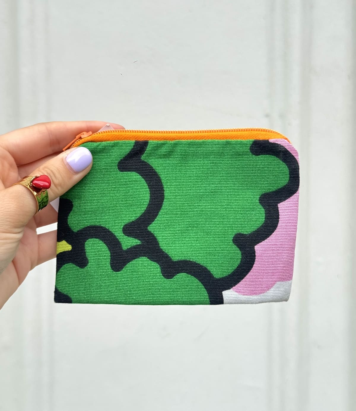 Main présentant une mini pochette verte upcyclée à la main