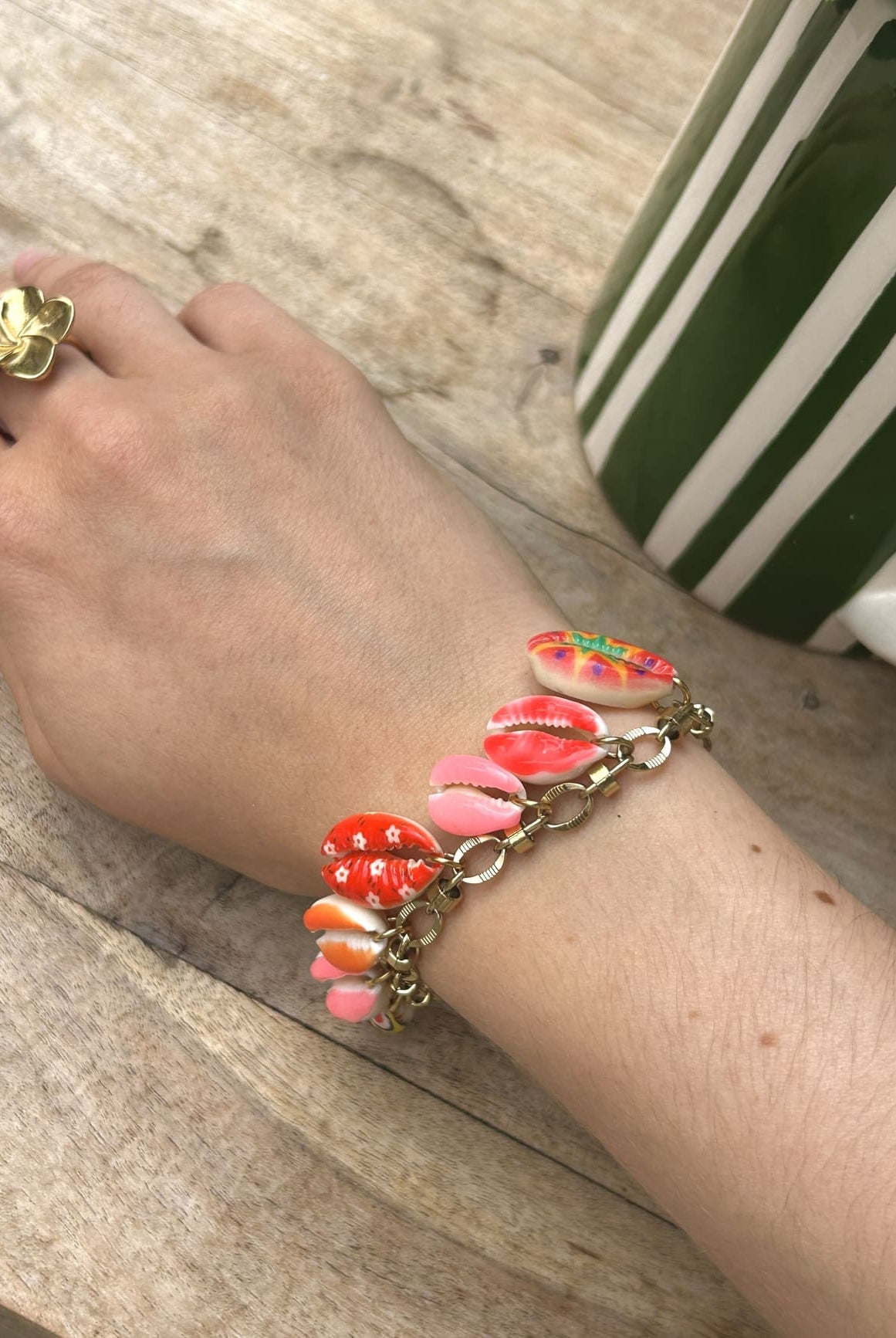 Bracelet à breloque coquillage dorée porté au poignet d’une femme