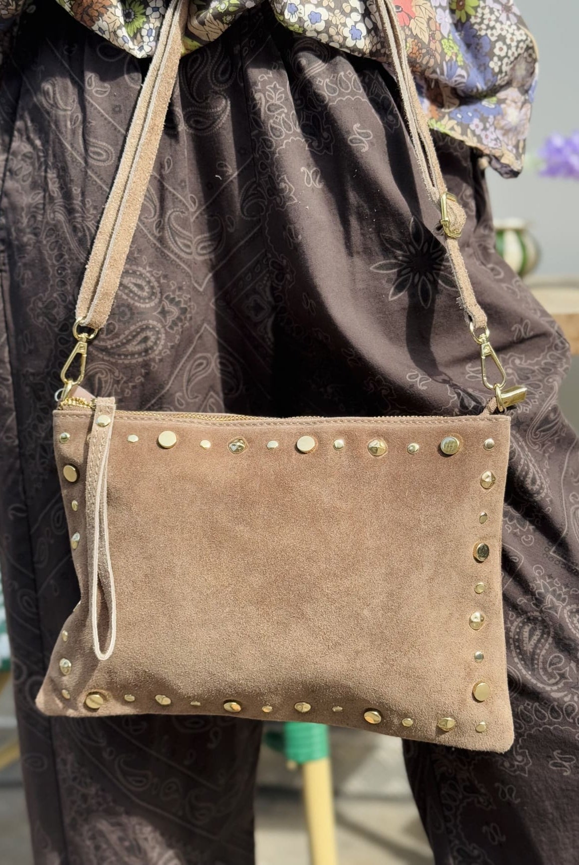 Gros plan sur un sac en daim pochette orné de clous sur tout le contour