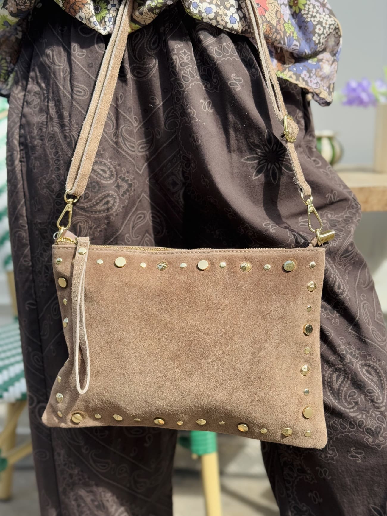 Gros plan sur un sac en daim pochette orné de clous sur tout le contour