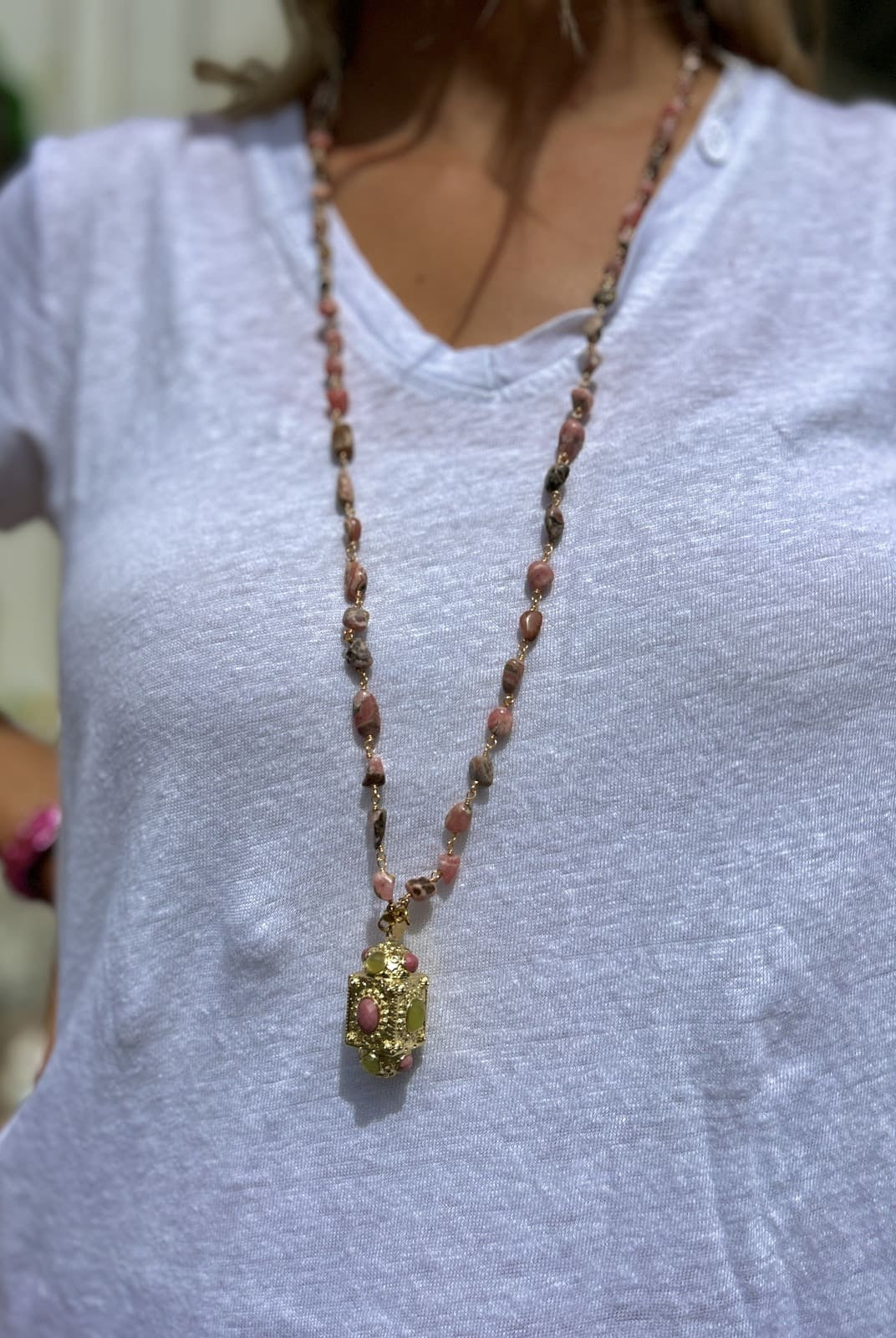 Femme portant le sautoir talisman orné de perles roses, style élégant et féminin