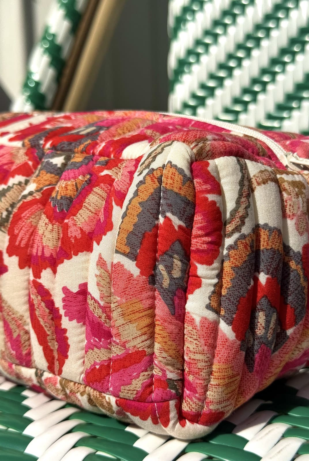 Gros plan sur la finition matelassée de la trousse fleurs rouges