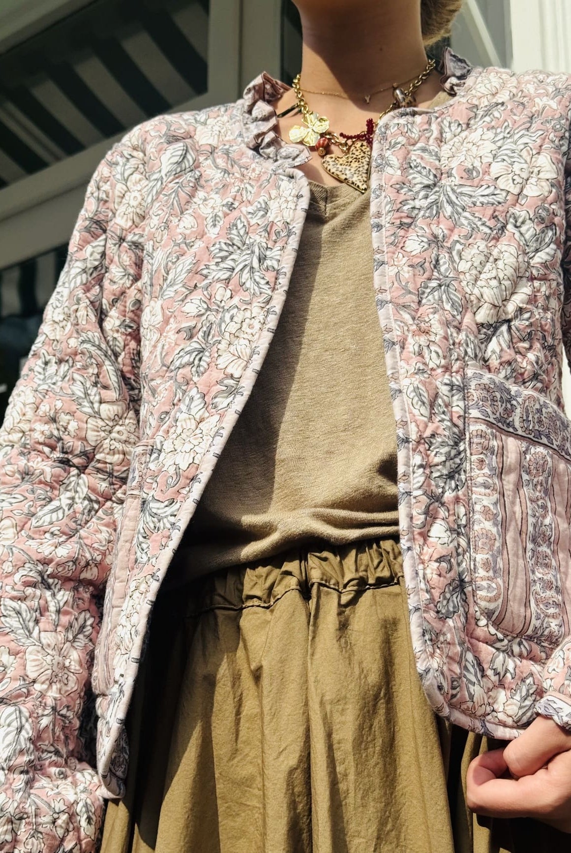 Plan légèrement contre-plongé sur la veste matelassée en coton rose et beige pour femme