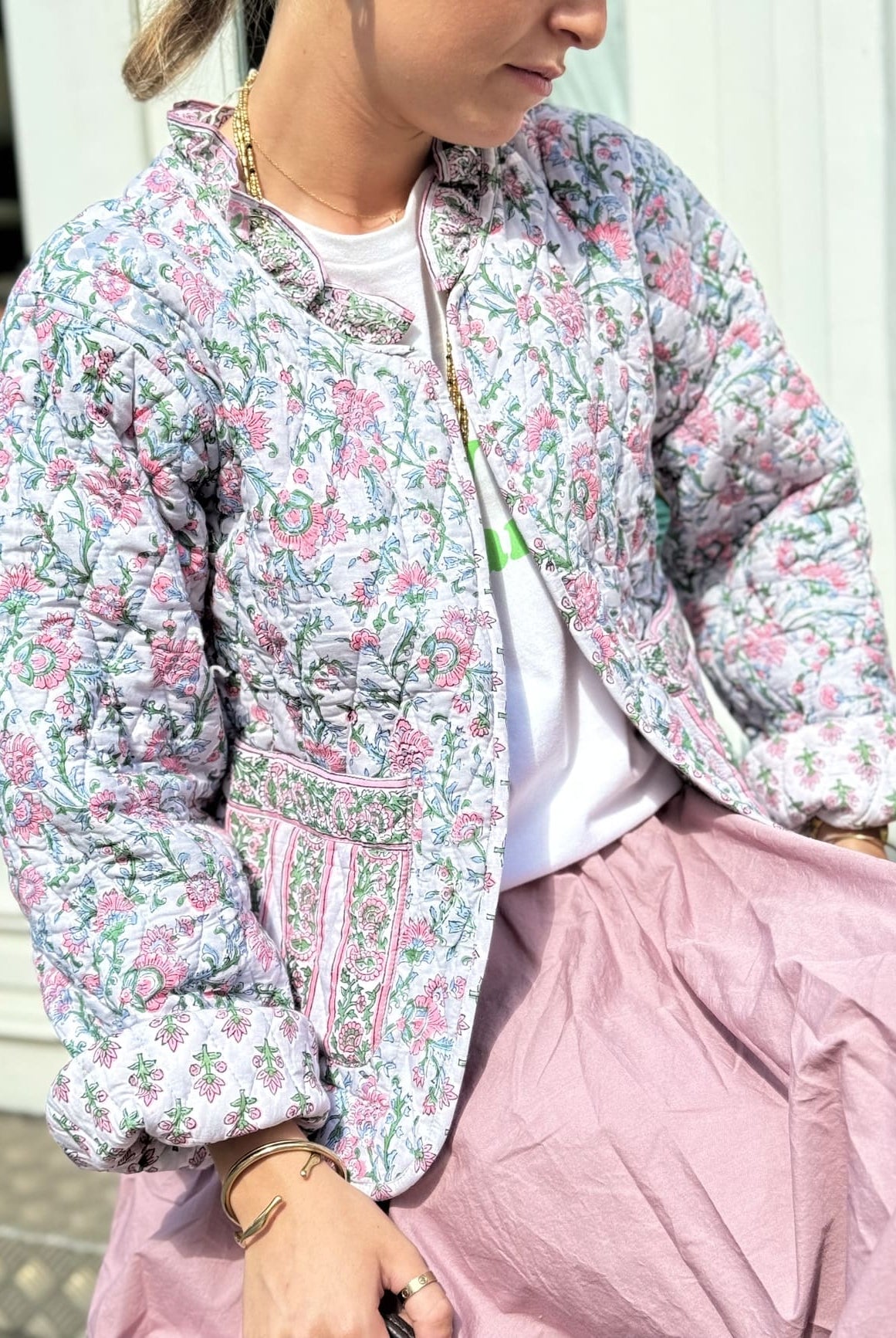 Femme assise portant la veste matelassée rose et verte