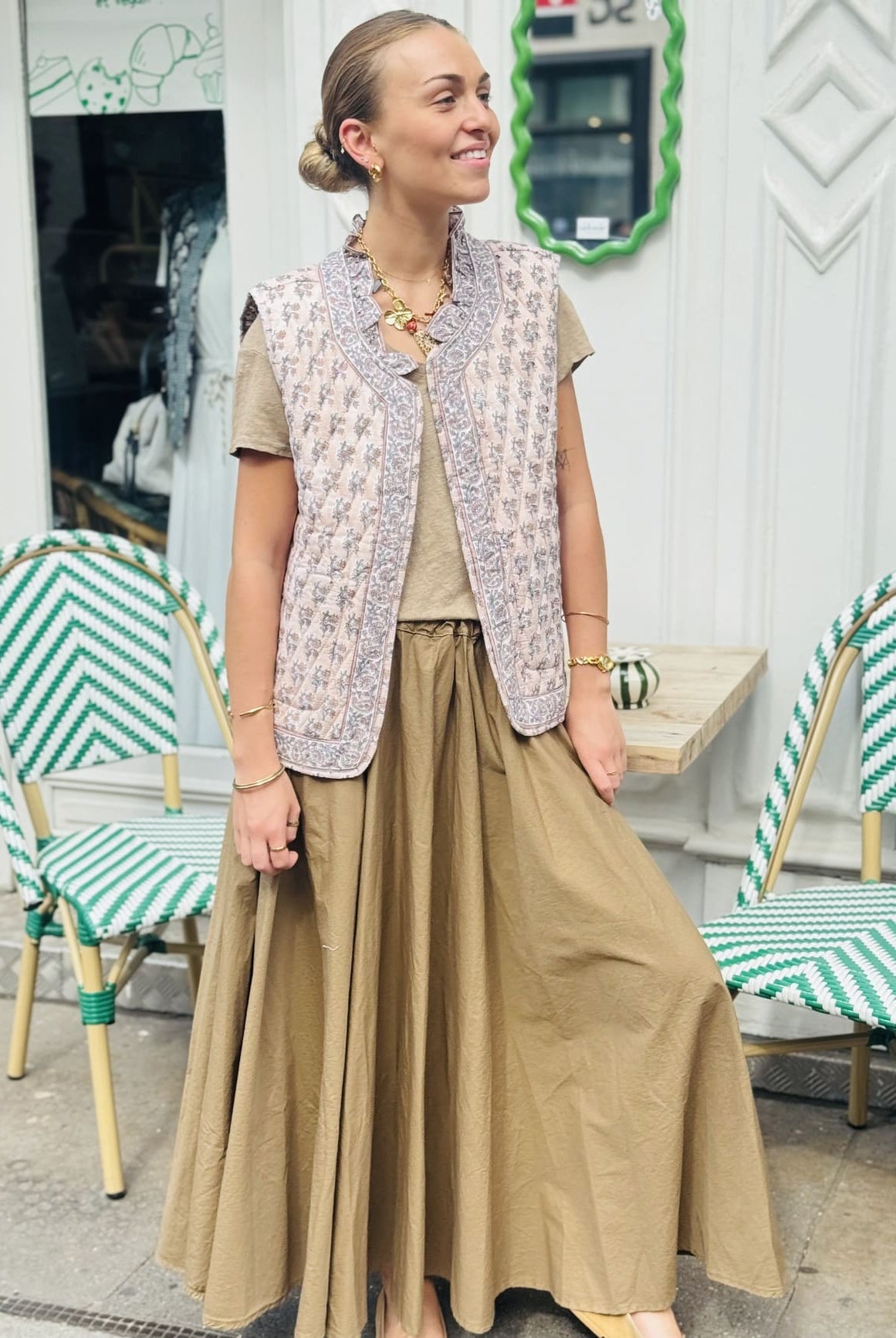 Veste matelassée sans manche beige et rose portée sur une jupe longue taupe