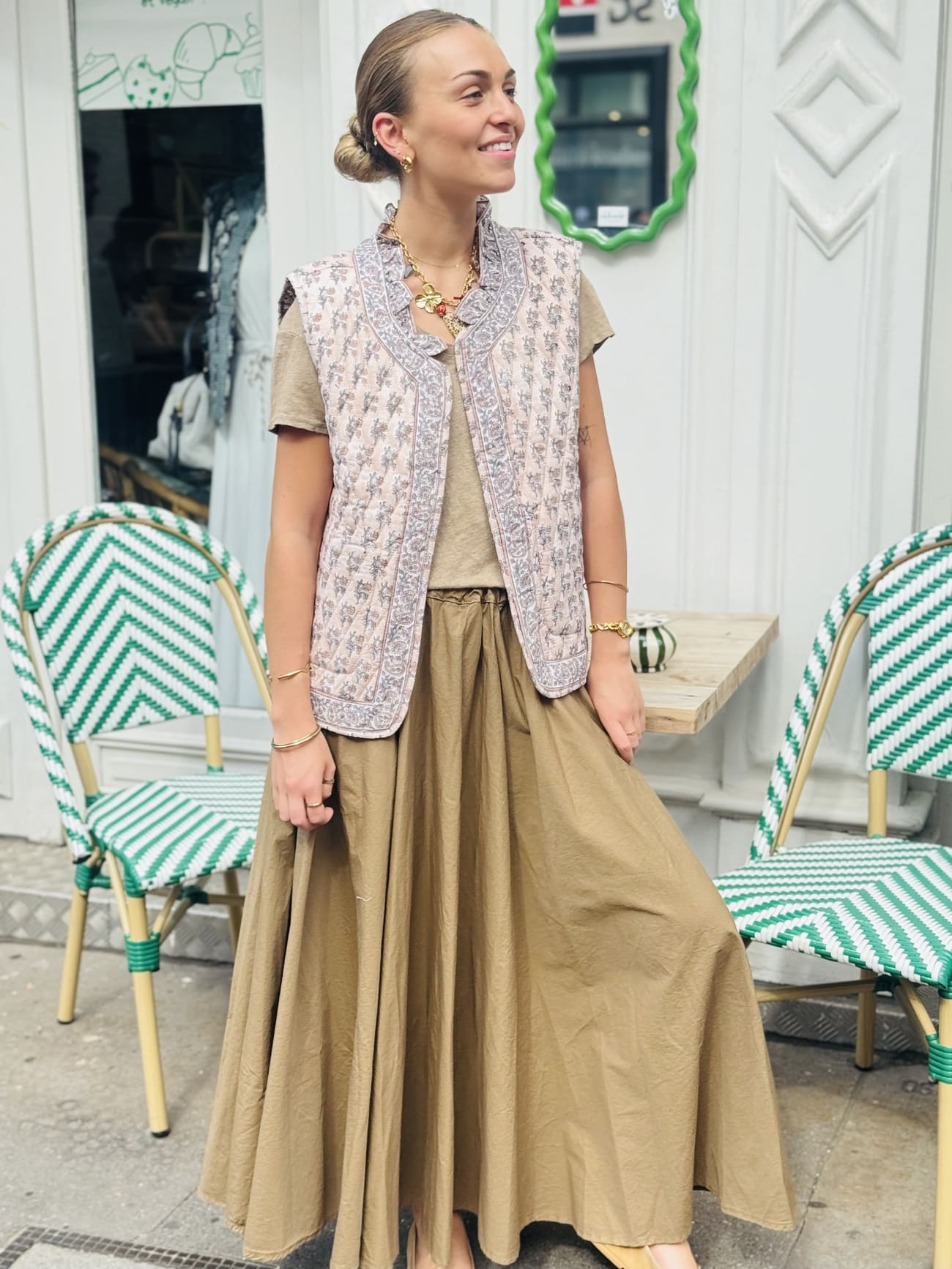 Veste matelassée sans manche beige et rose portée sur une jupe longue taupe