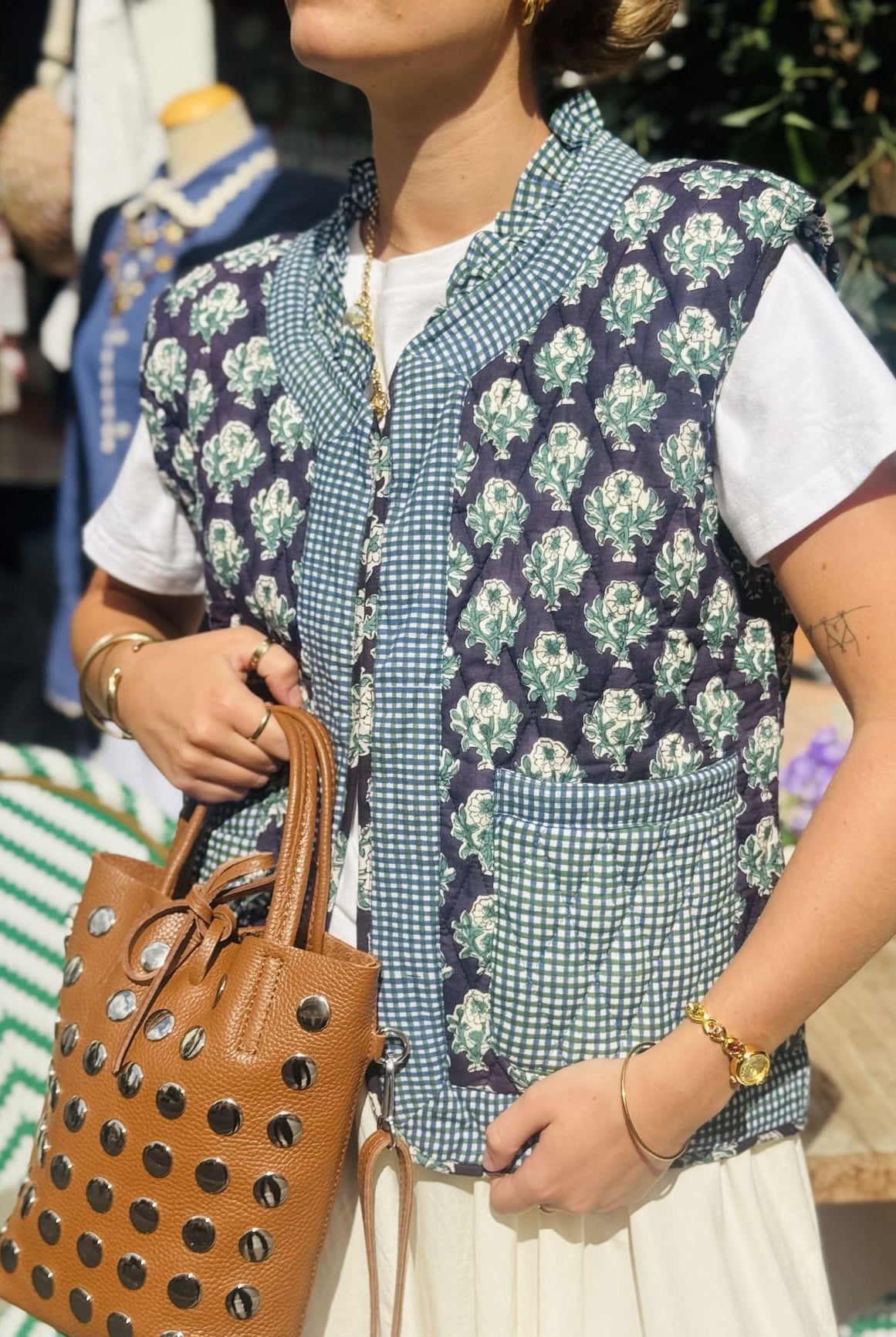 Femme portant la veste matelassée sans manche noir et verte avec un sac en cuir