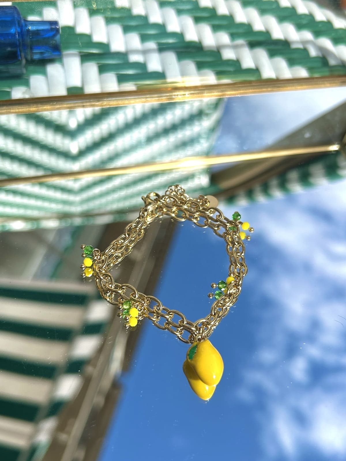 Bracelet breloque citron avec breloque fruitée colorée sur chaîne dorée, exposé sur fond clair