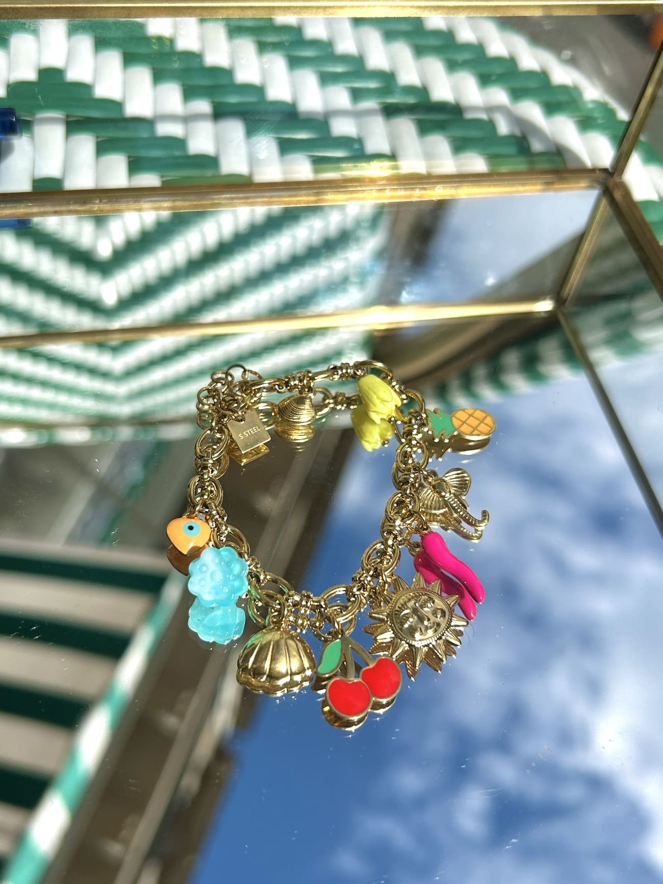 Bracelet breloque avec charms soleil et ananas, exposé sur fond clair